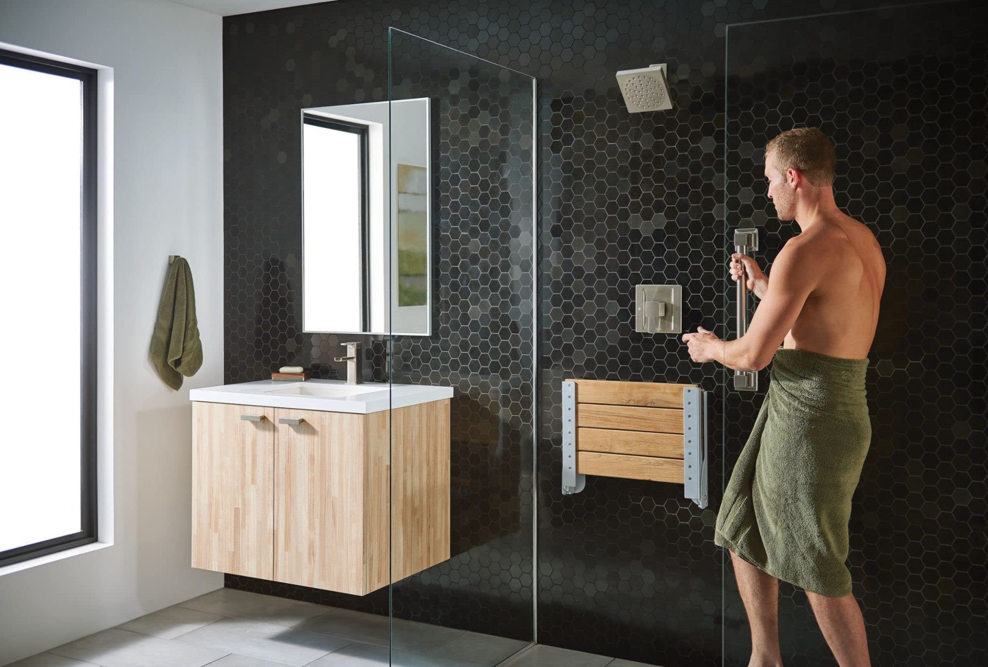 Brushed nickel shower trim kit with single handle mounted on black hexagonal tile shower wall.