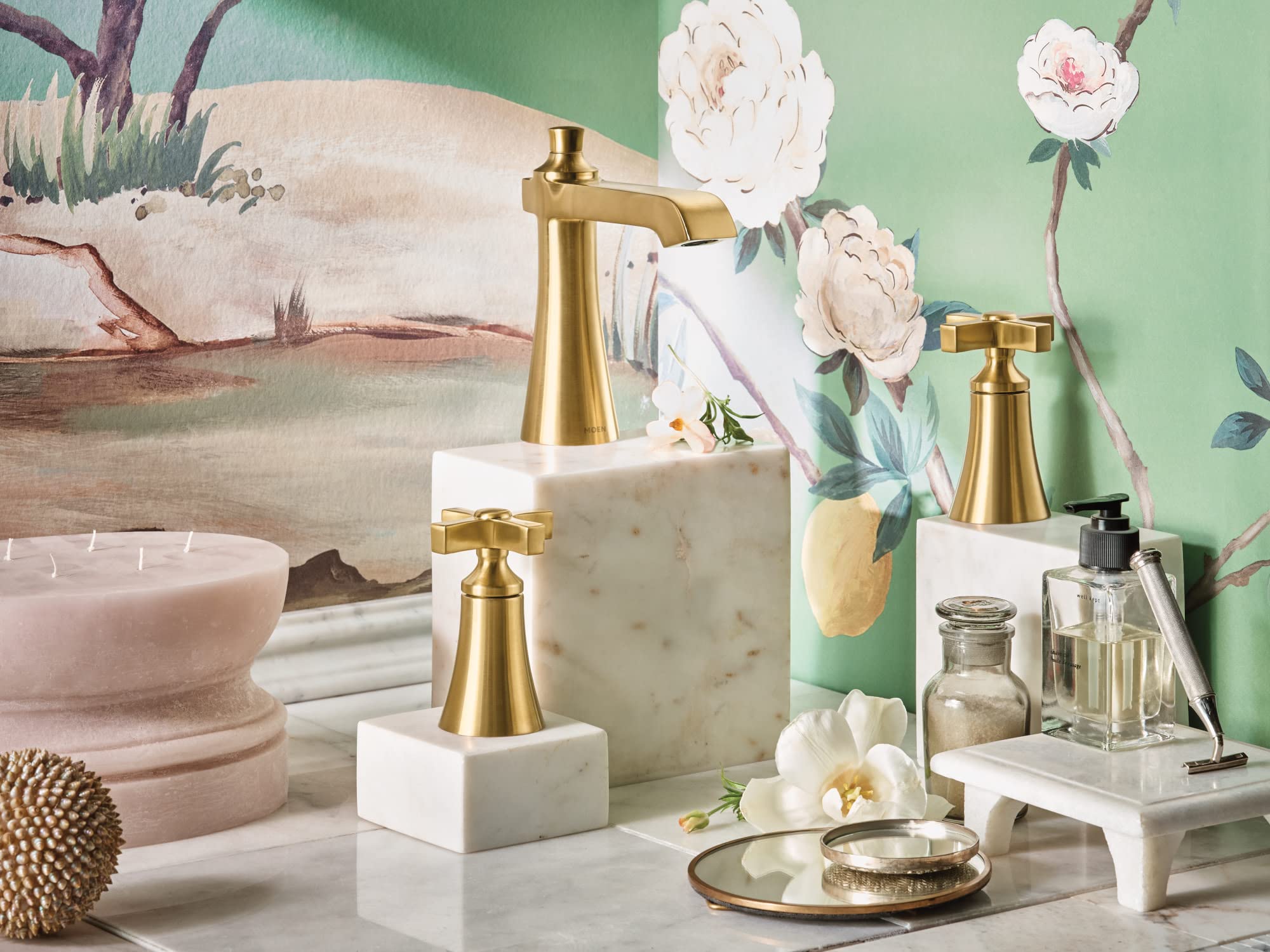 Brushed gold two-handle bathroom faucet with cross handles and 8-inch widespread configuration on marble base.