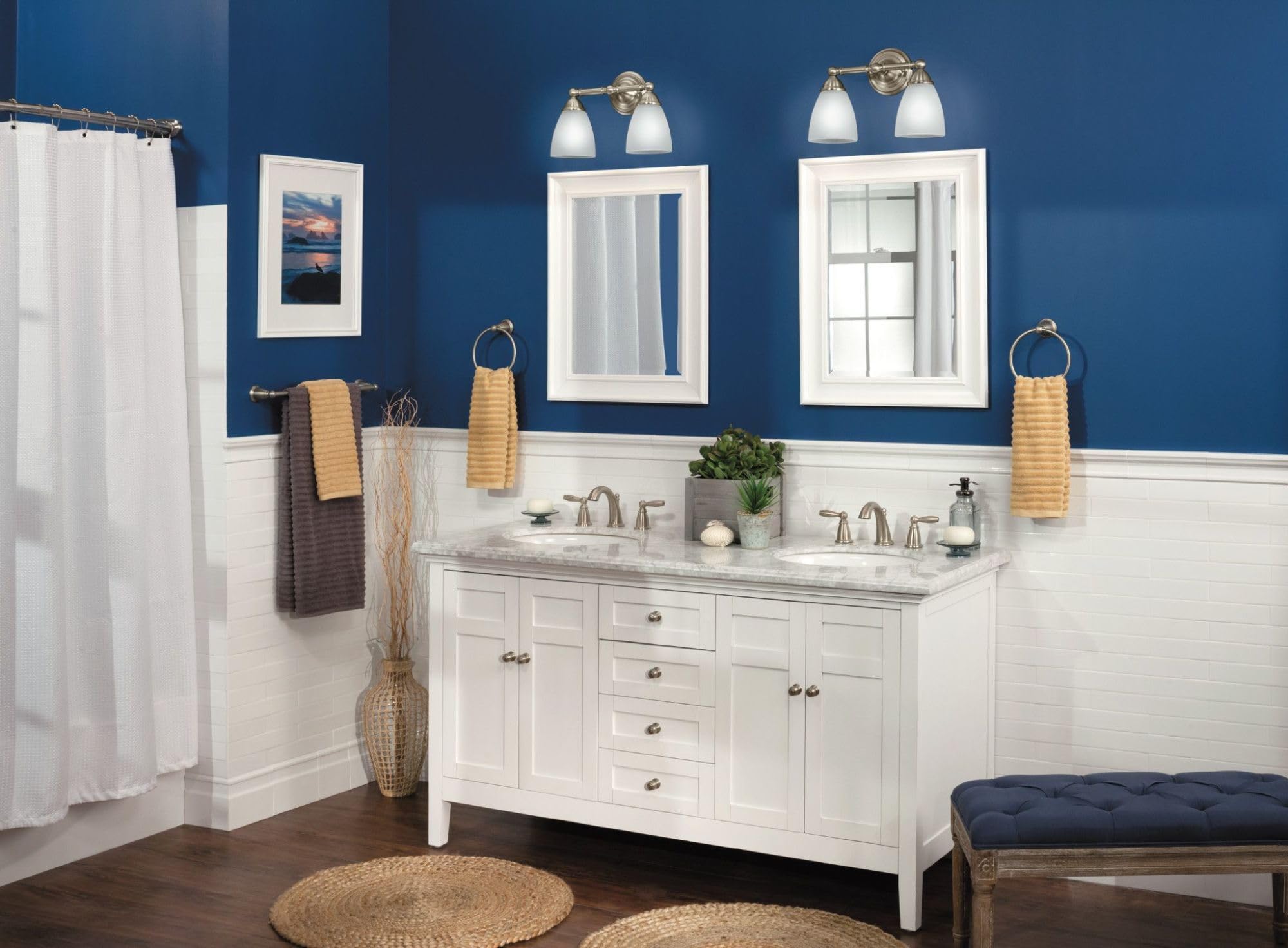 Brushed nickel wall-mounted towel bar holding folded towels above bathroom vanity sink.