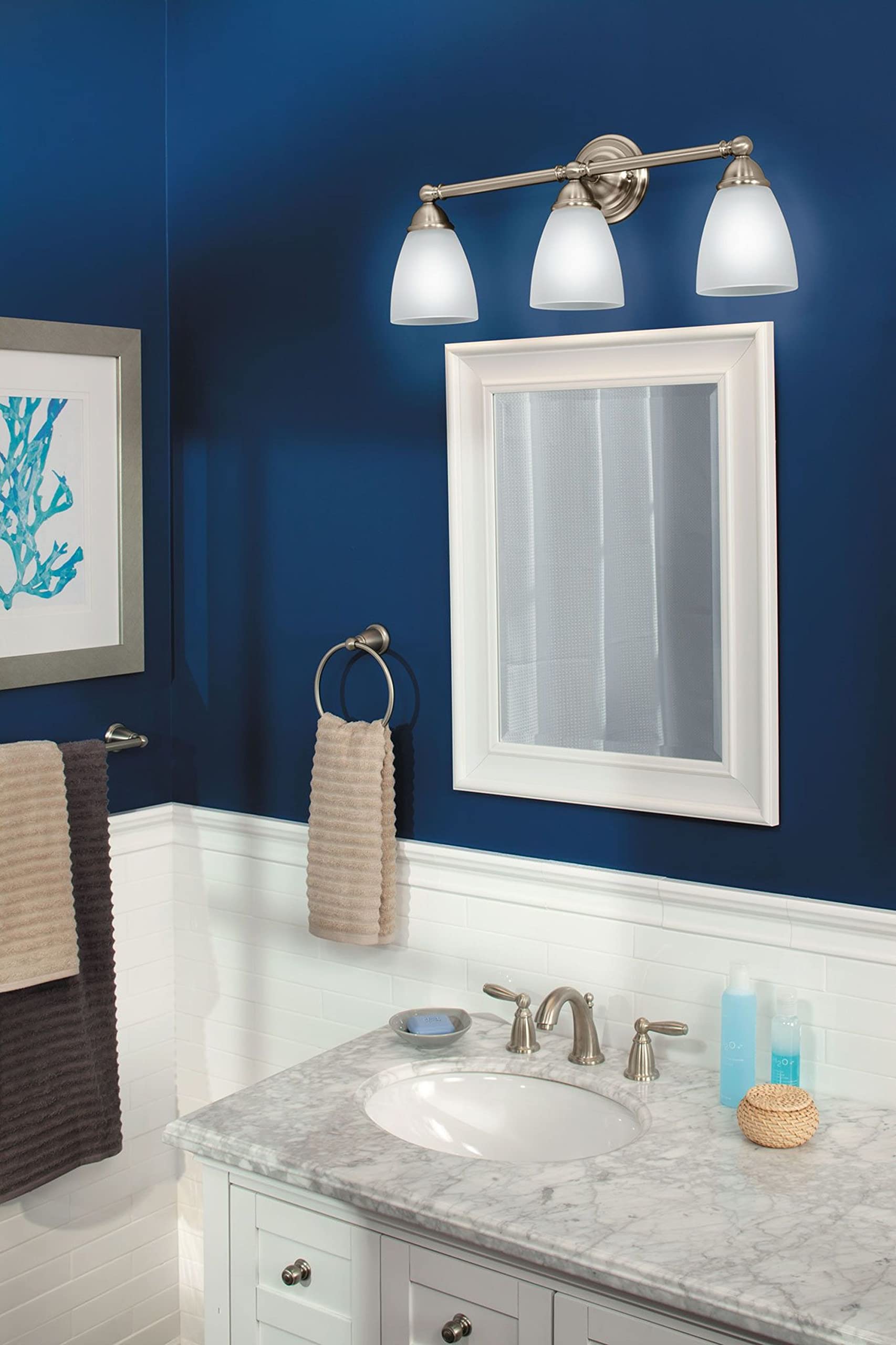Brushed nickel towel ring mounted on blue bathroom wall below mirror, holding folded towels.