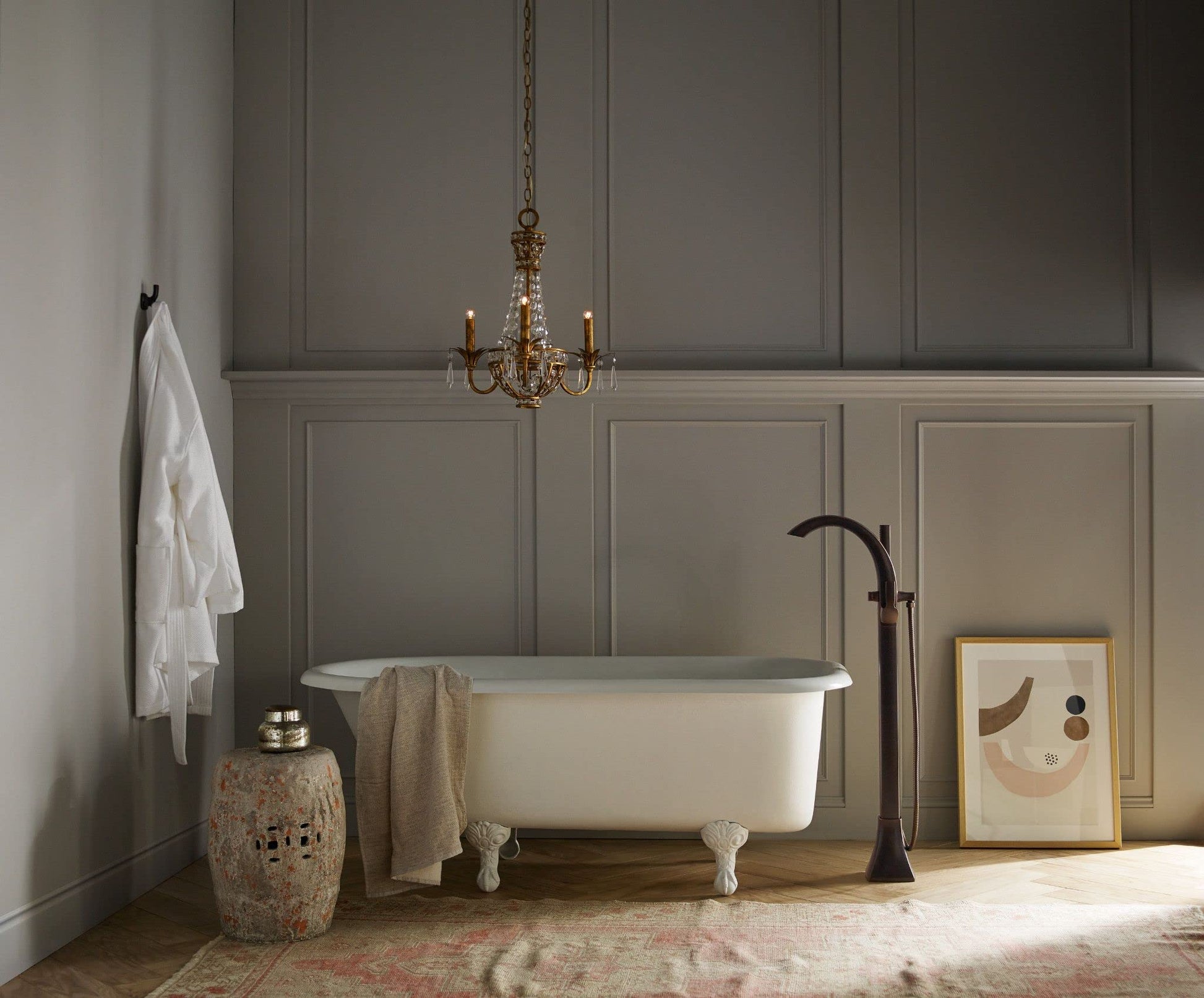Oil rubbed bronze freestanding tub filler with single handle and detachable handshower, displayed next to white soaking tub.