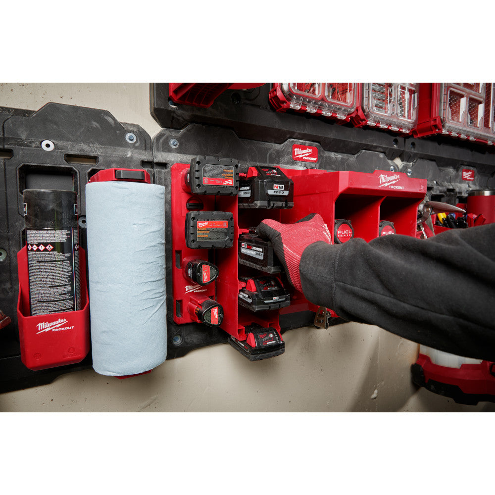 Red and black Milwaukee PACKOUT battery rack holding multiple M18 batteries mounted on wall with storage organizers.