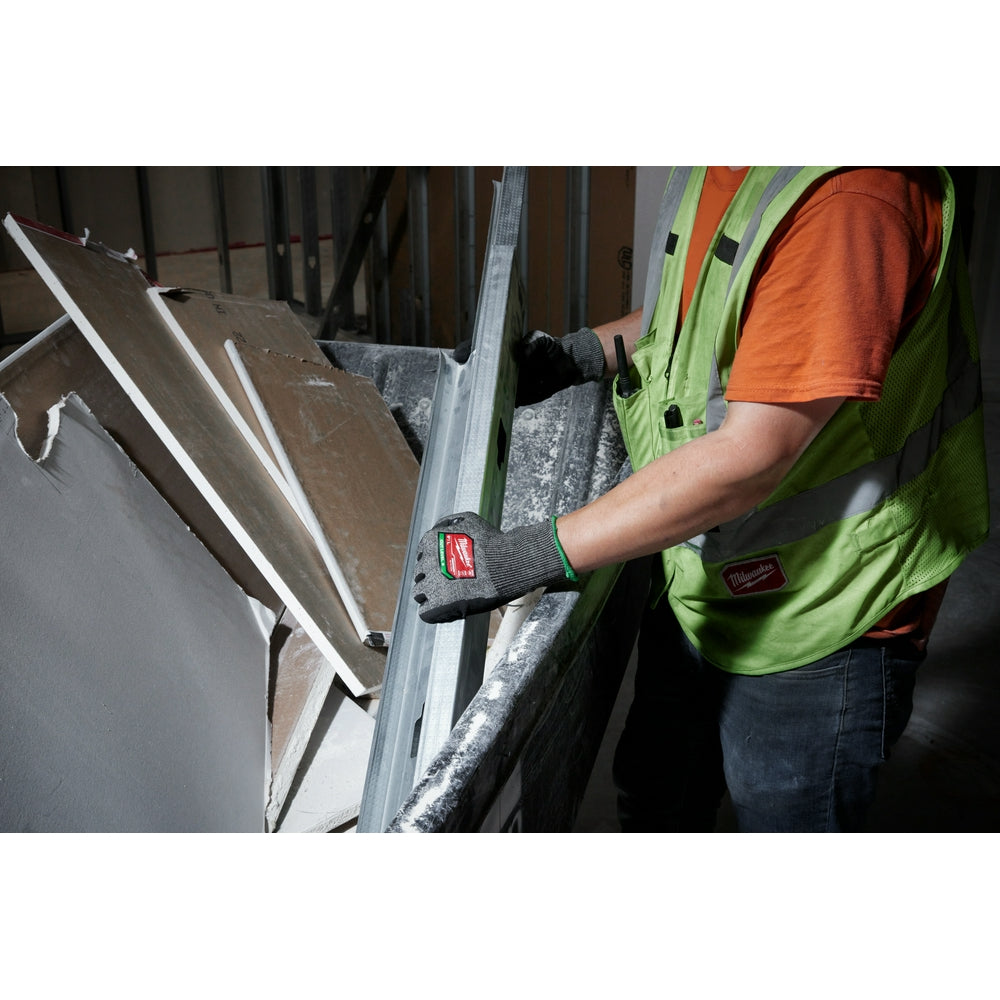 Worker wearing black and gray cut-resistant gloves while handling sheet metal.