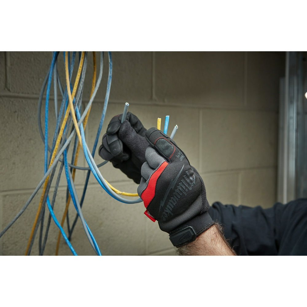 Black and red work glove with gray palm gripping colored electrical wires.
