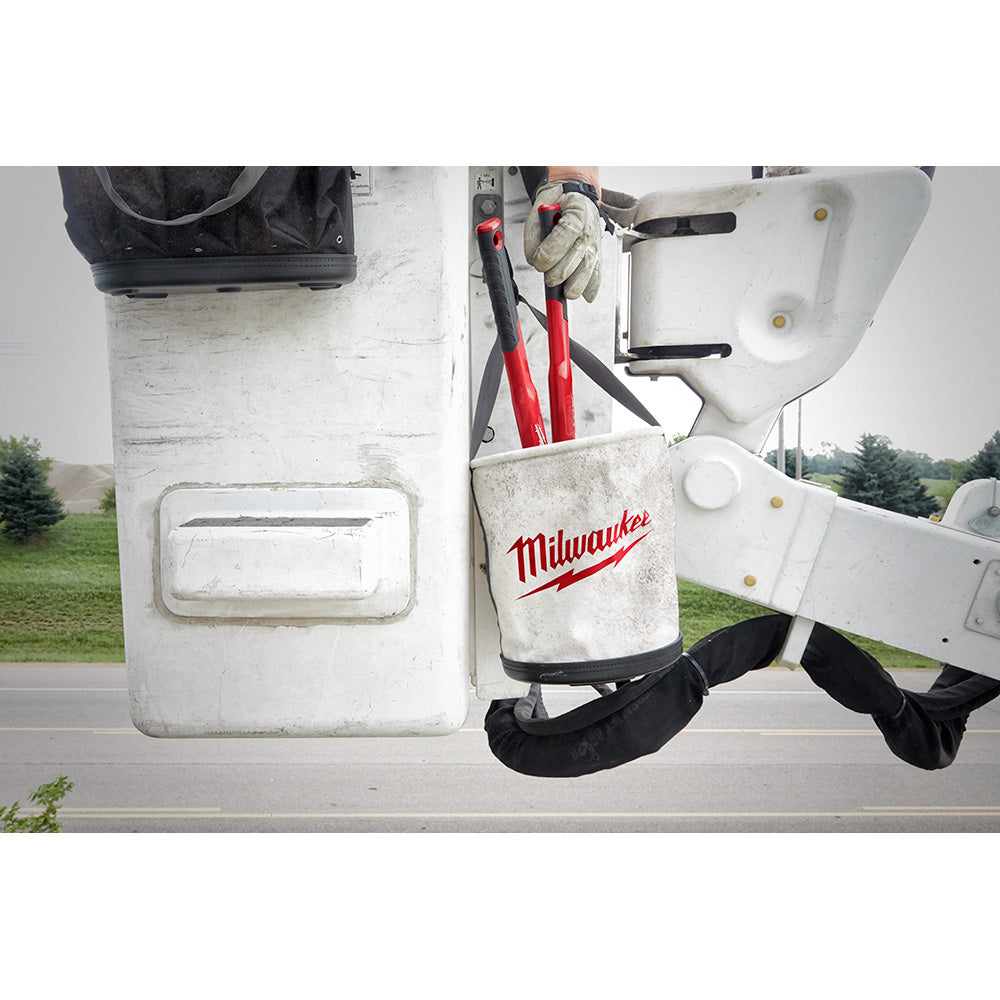 Milwaukee canvas utility bucket with red logo holding tools, mounted on white surface with black handles and metal rivets.