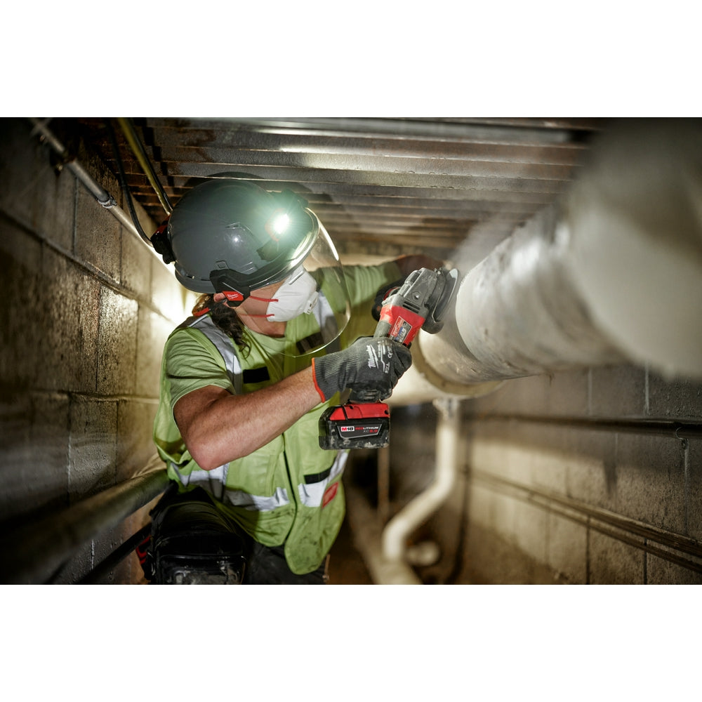 Worker wearing gray helmet with clear full face shield mount attached while operating power tool in industrial setting.