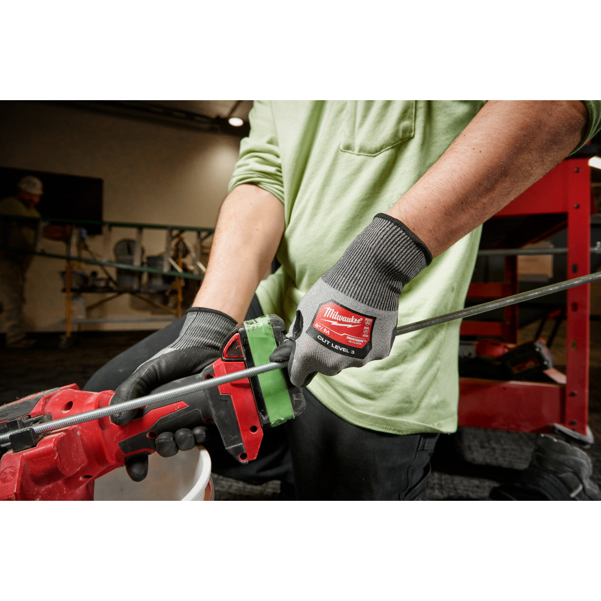 Black polyurethane dipped work gloves with gray knit cuffs worn while gripping a red tool.