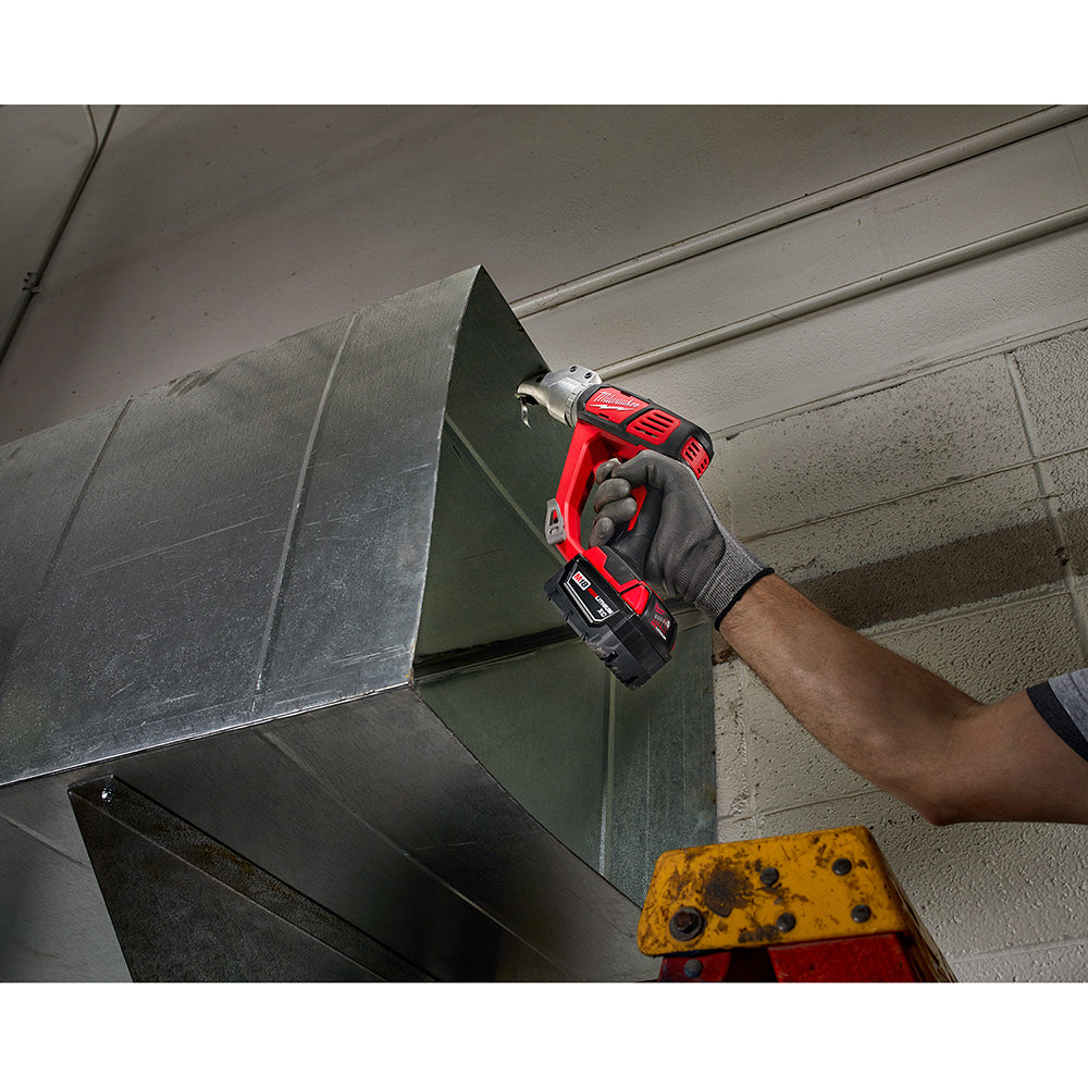Red and black cordless shear with battery pack being used to cut sheet metal.