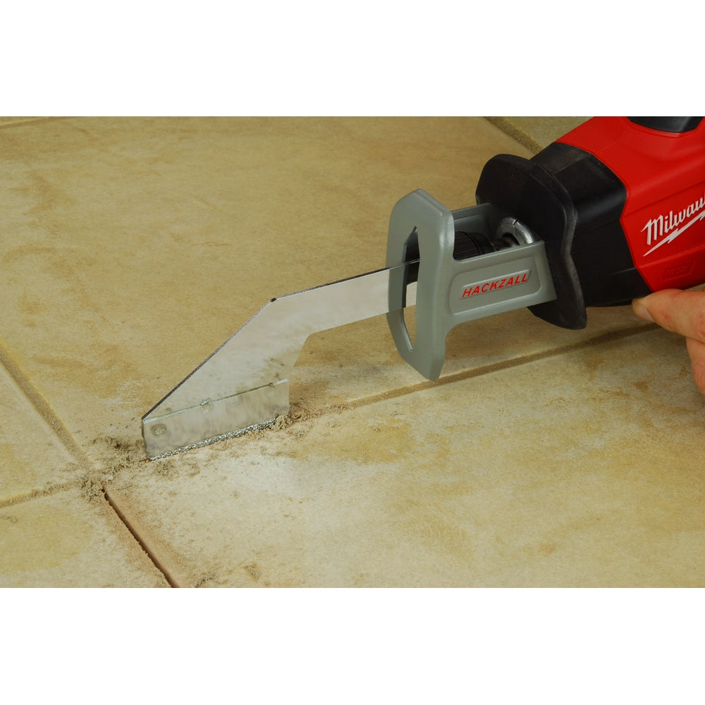 Milwaukee grout removal tool with gray blade attachment removing grout from tile joints on floor.