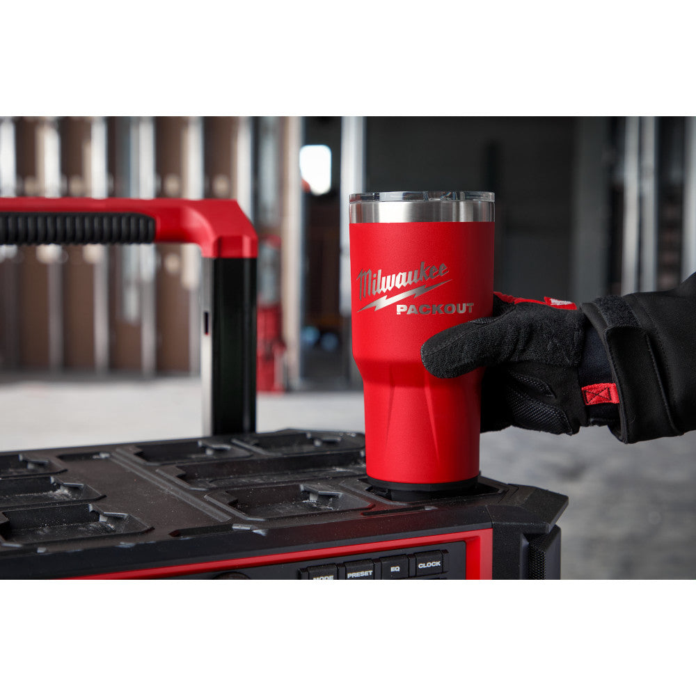 Red insulated tumbler with stainless steel top and Milwaukee Packout branding, sitting on a tool organizer.