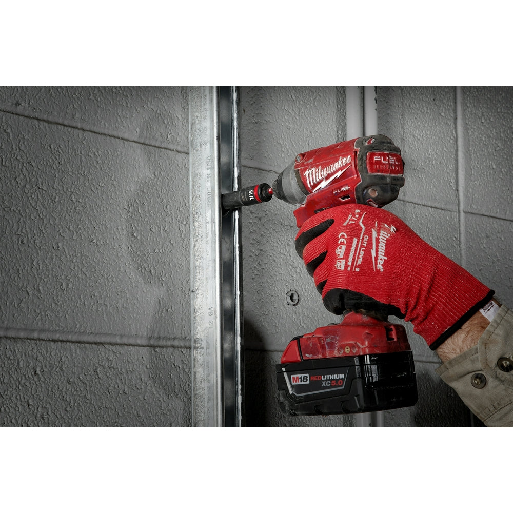 Red Milwaukee drill with hex shank adapter attached, held by gloved hand against metal surface.