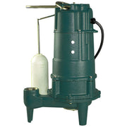 Green cast iron grinder pump with attached float switch and discharge pipe on white background.