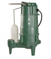 Green cast iron grinder pump with white float switch and outlet pipe on four legs.