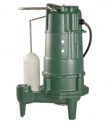 Green cast iron grinder pump with white float switch and outlet pipe on four legs.