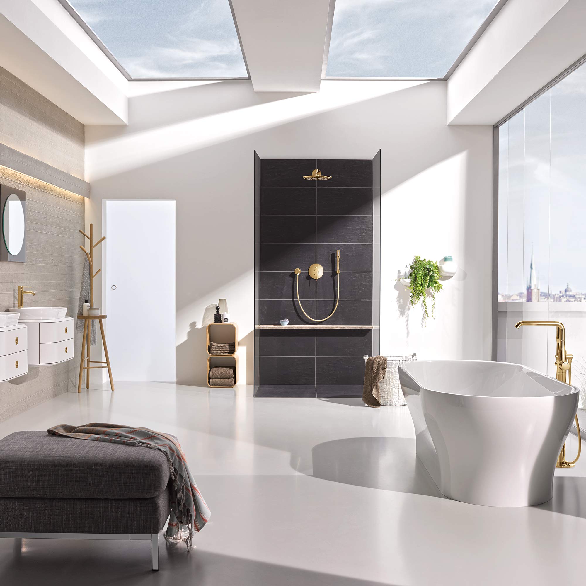 Brushed gold single-handle faucet with curved spout and hand shower mounted on white freestanding tub in modern bathroom.