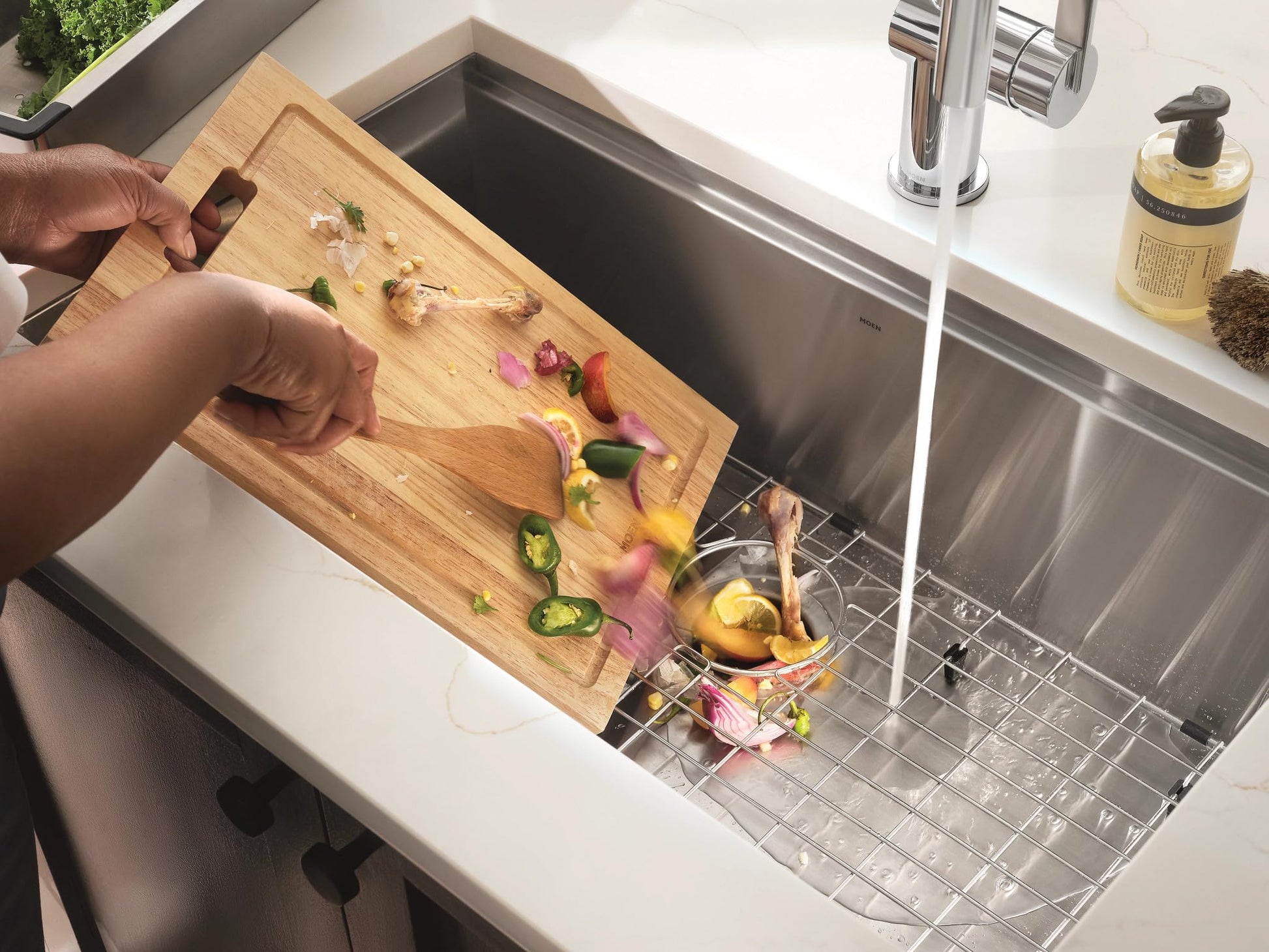 Stainless steel undermount sink with wooden cutting board positioned over drying rack containing fresh vegetables and yellow 