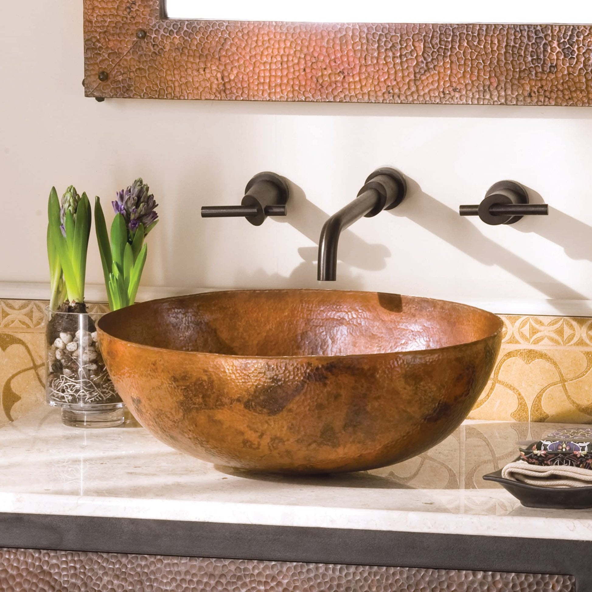 Antique copper oval bathroom sink with hammered texture and oil-rubbed bronze wall-mounted faucet.