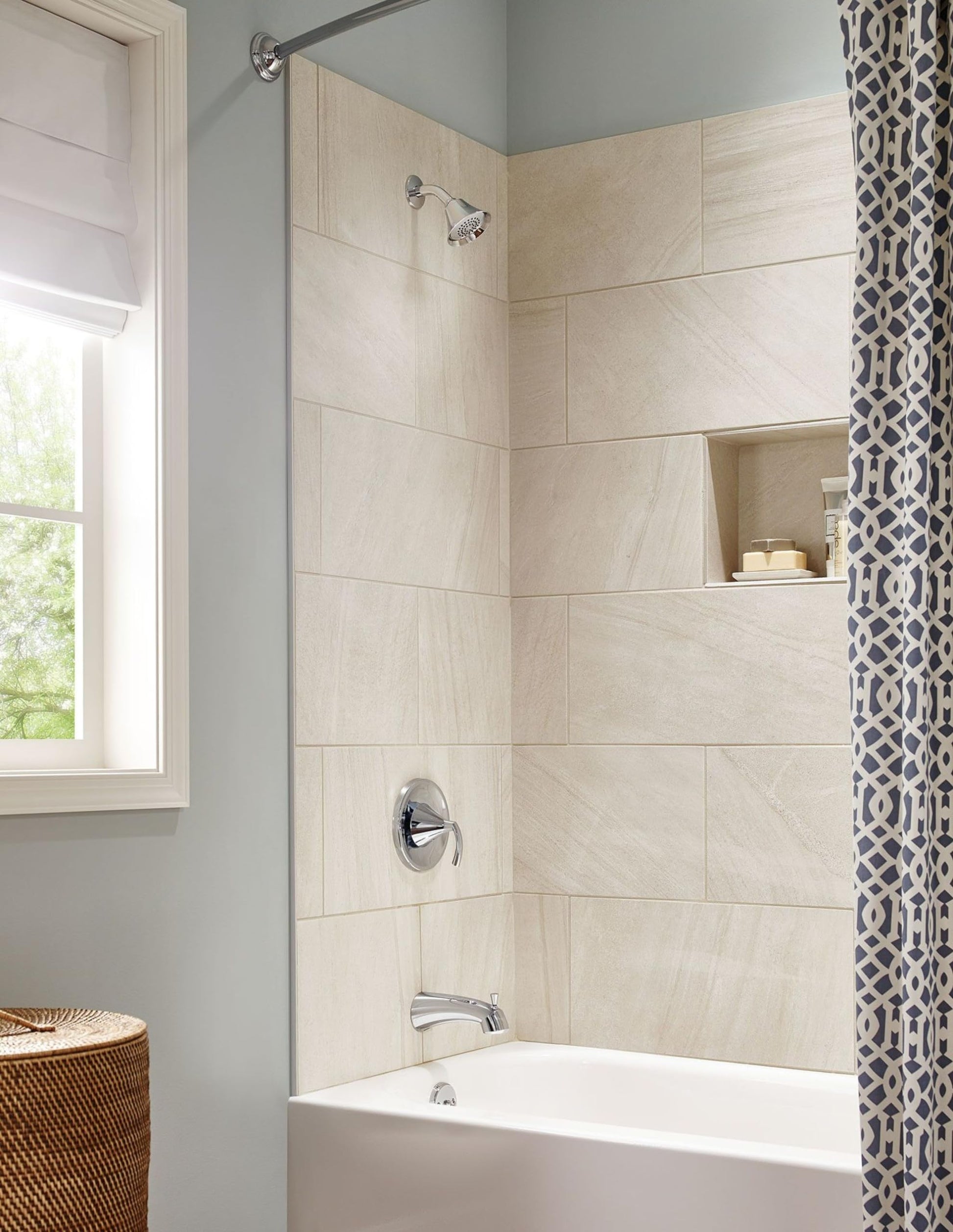 Chrome single-handle tub and shower trim with round escutcheon installed on cream tile surround above white bathtub.