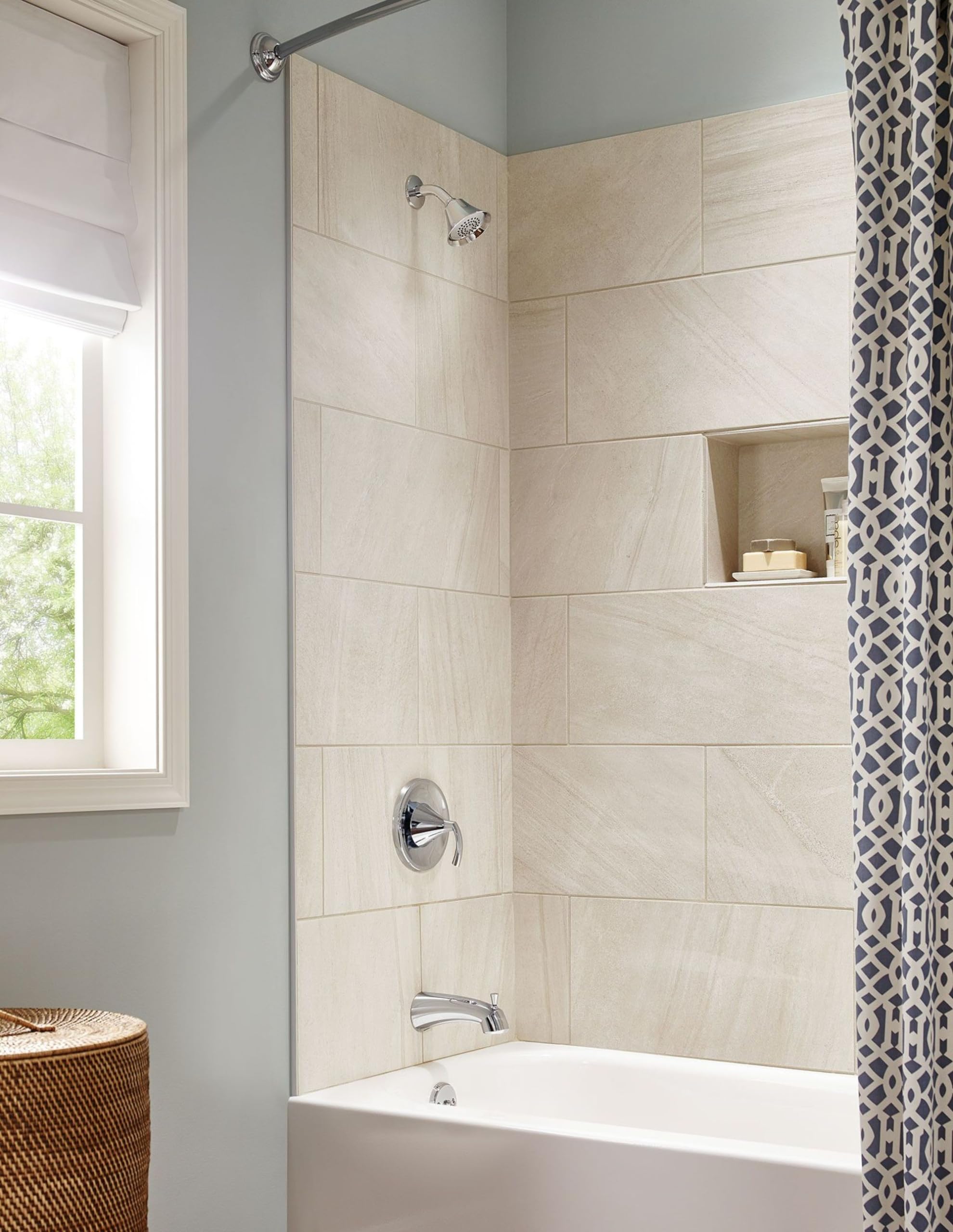 Chrome single-handle tub and shower trim with round escutcheon installed on cream tile surround above white bathtub.