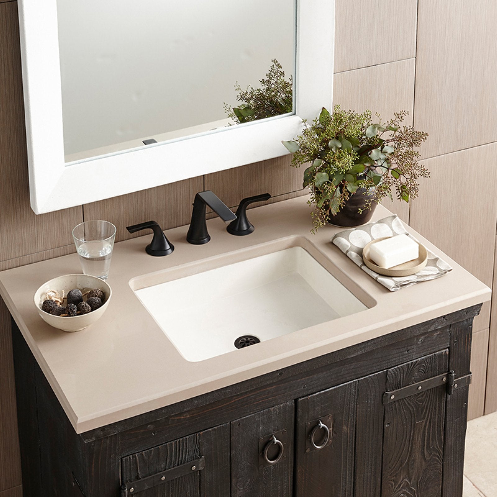 Rectangular slate-colored undermount bathroom sink with cream countertop and black faucet installed on dark wood vanity.