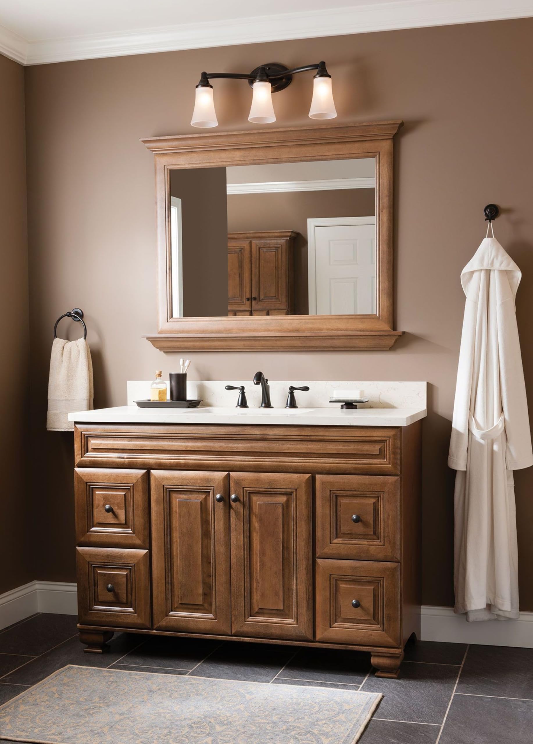 Oil-rubbed bronze vanity light with three frosted glass shades mounted above a bathroom sink.