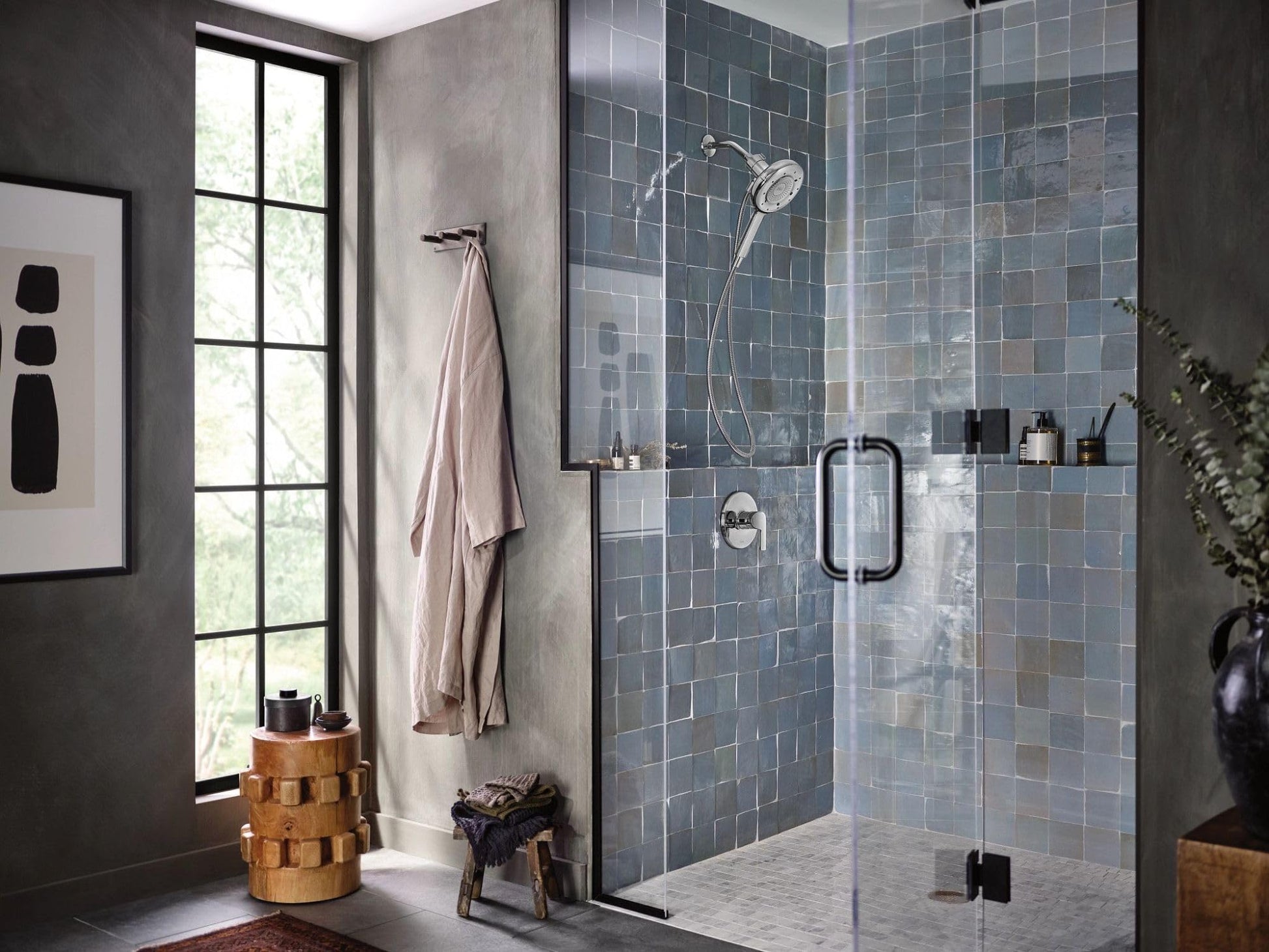 Chrome single-handle tub and shower trim kit with hand shower and control valve mounted on tiled shower wall.