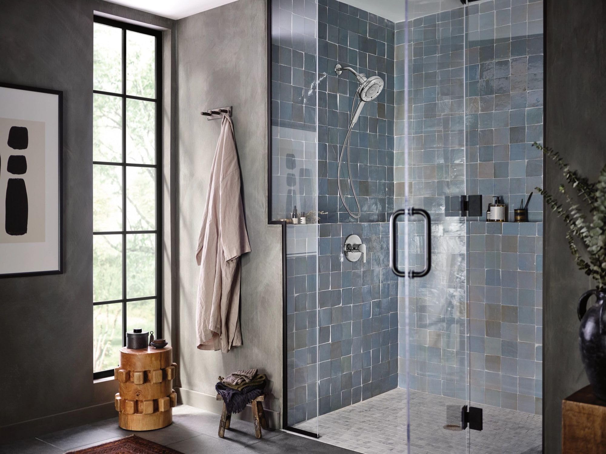 Chrome single-handle tub and shower trim kit with hand shower and control valve mounted on tiled shower wall.