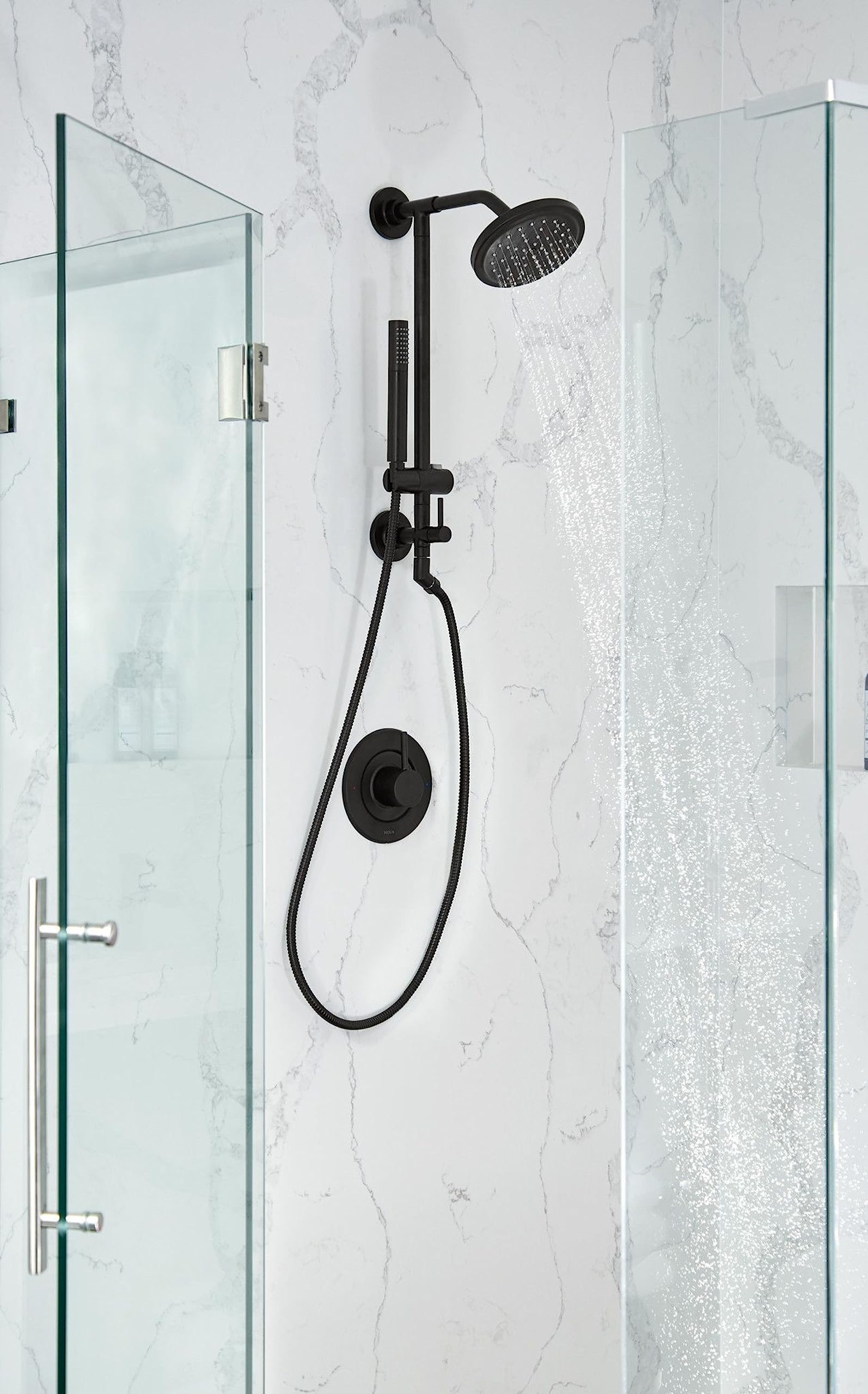 Matte black shower system with overhead rainhead, handheld showerhead on vertical slidebar, and control valve mounted on marb