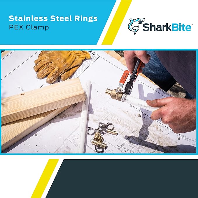 Stainless steel PEX clamp rings displayed on work surface with plumbing tools and blueprints during installation.
