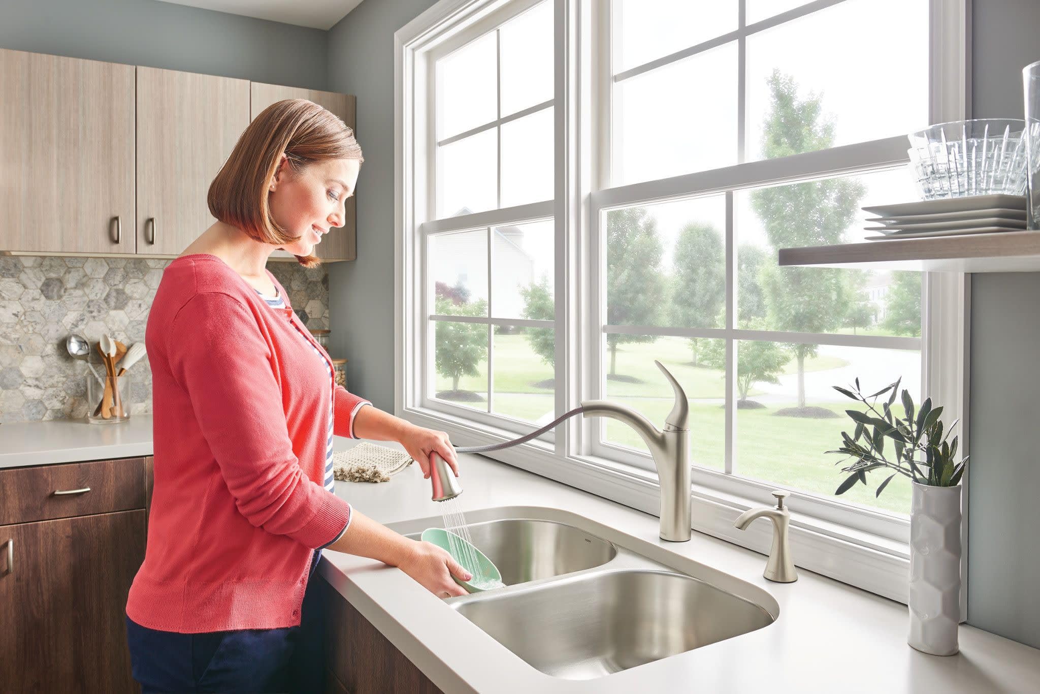 Spot resist stainless steel single-handle kitchen faucet with pullout spray head mounted above a double basin sink.