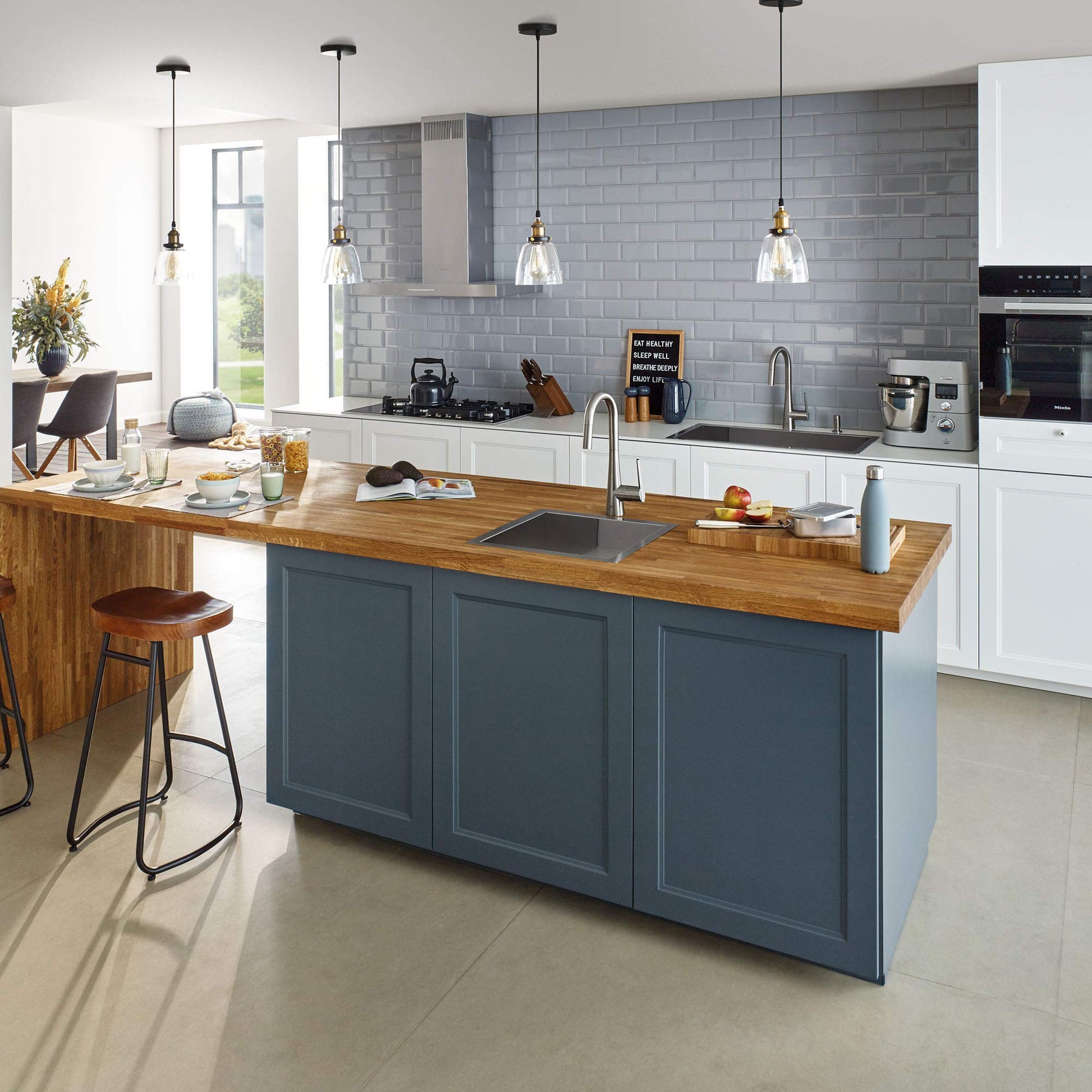 Stainless steel single-handle pull-down faucet with flexible spray head installed at kitchen island sink with wood countertop