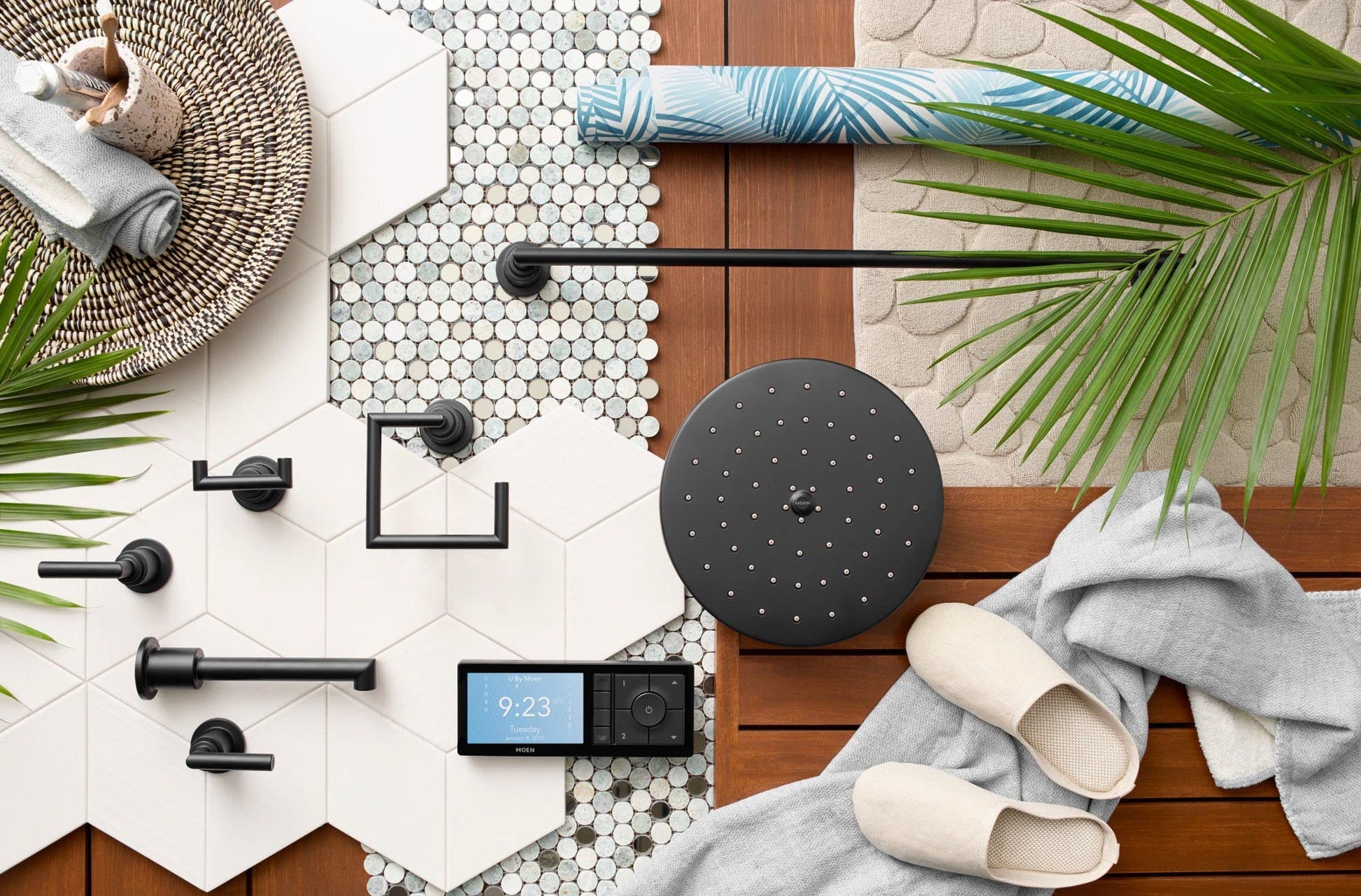 Matte black round body spray head with perforations displayed among coordinating matte black bathroom fixtures on hexagonal t