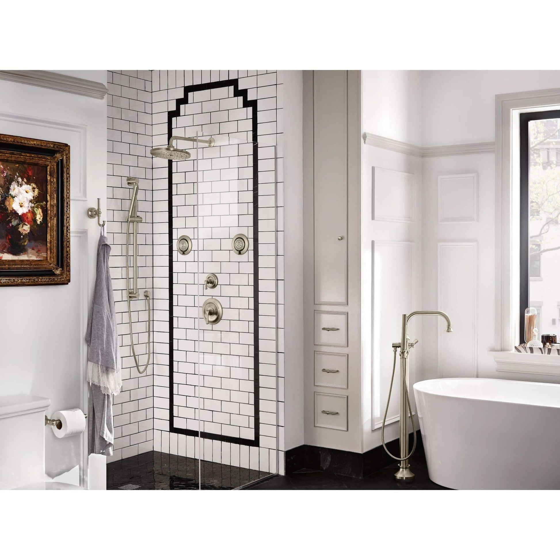 Matte black freestanding tub filler with single handle and matching handshower, installed next to white soaking tub in bathro