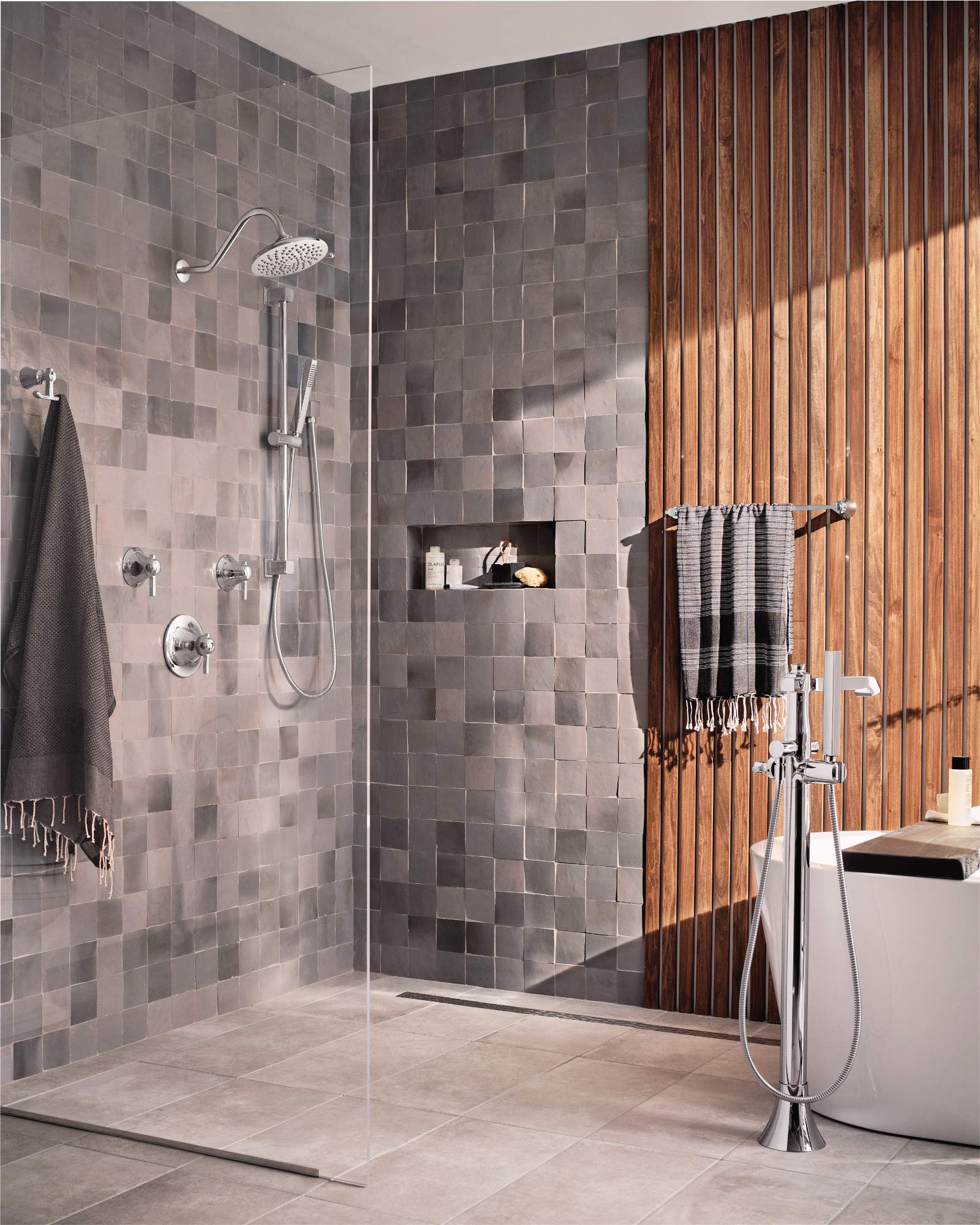 Chrome shower trim kit with round showerhead, hand shower, and wall-mounted controls installed in tiled bathroom.