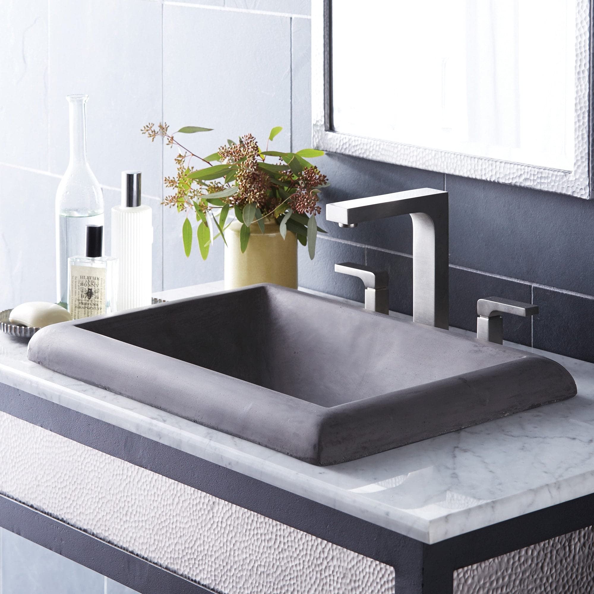 Ash-colored rectangular bathroom sink with rolled rim edges and sloped interior, installed on white marble countertop with ch