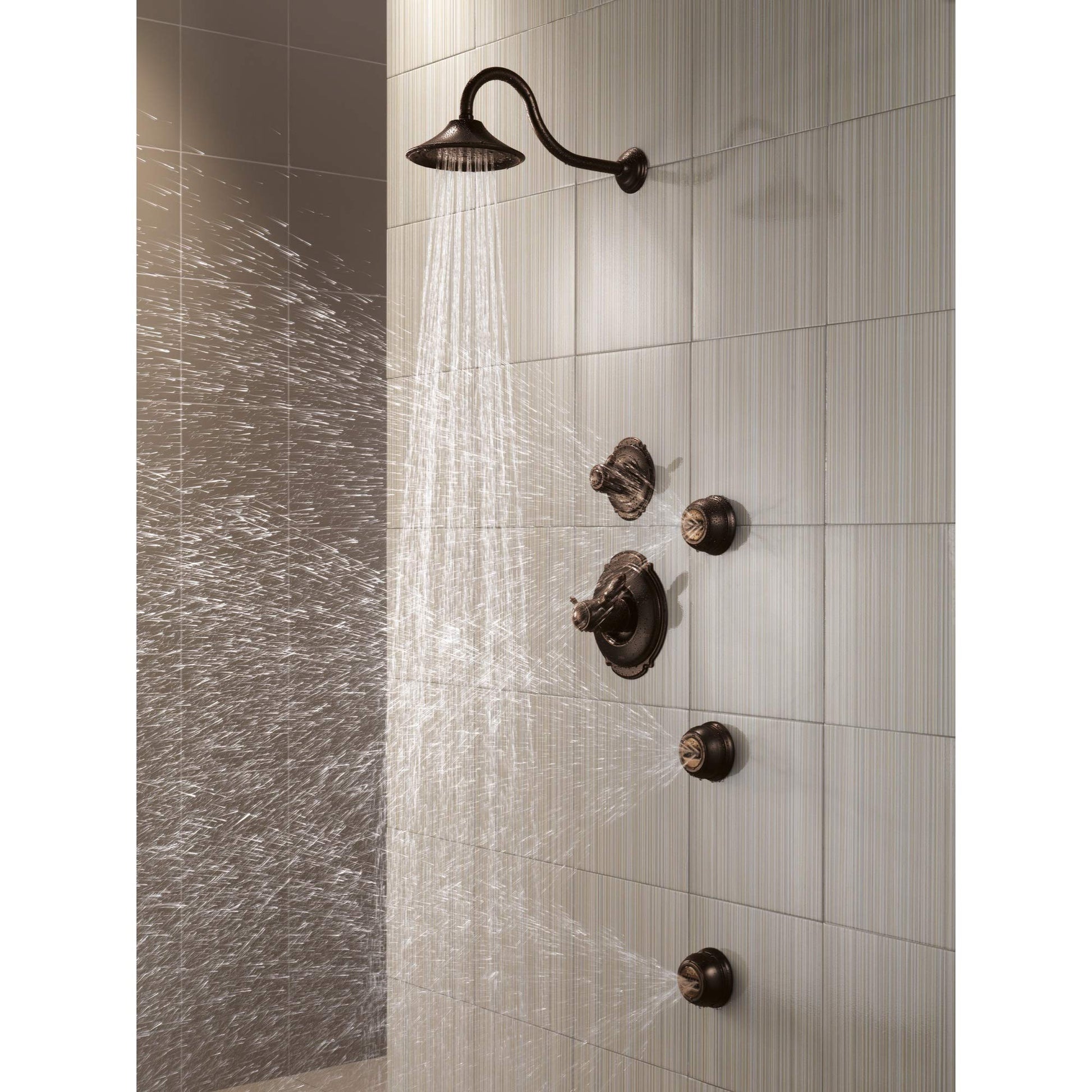 Venetian bronze shower head with curved arm and multiple wall-mounted control knobs installed in tiled shower enclosure.