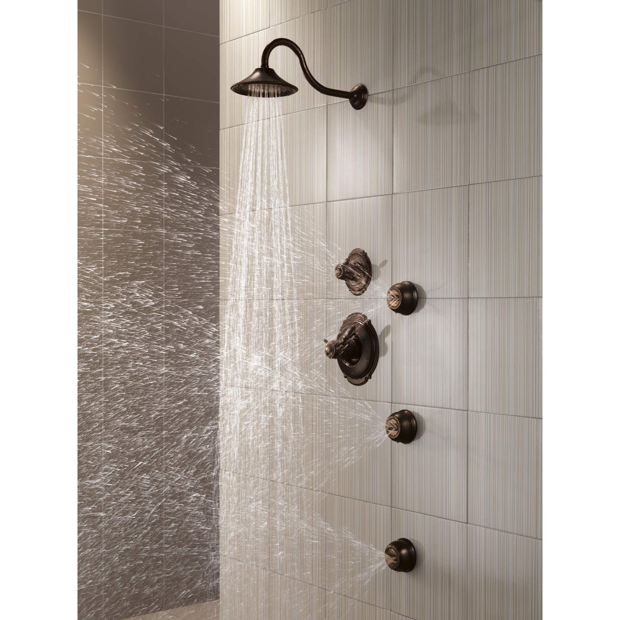 Venetian bronze shower head with curved arm and multiple wall-mounted control knobs installed in tiled shower enclosure.
