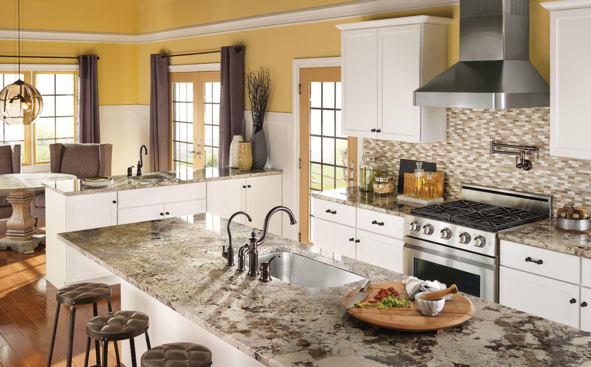 Oil rubbed bronze wall-mount pot filler faucet with swing arm and folding spout above kitchen sink.