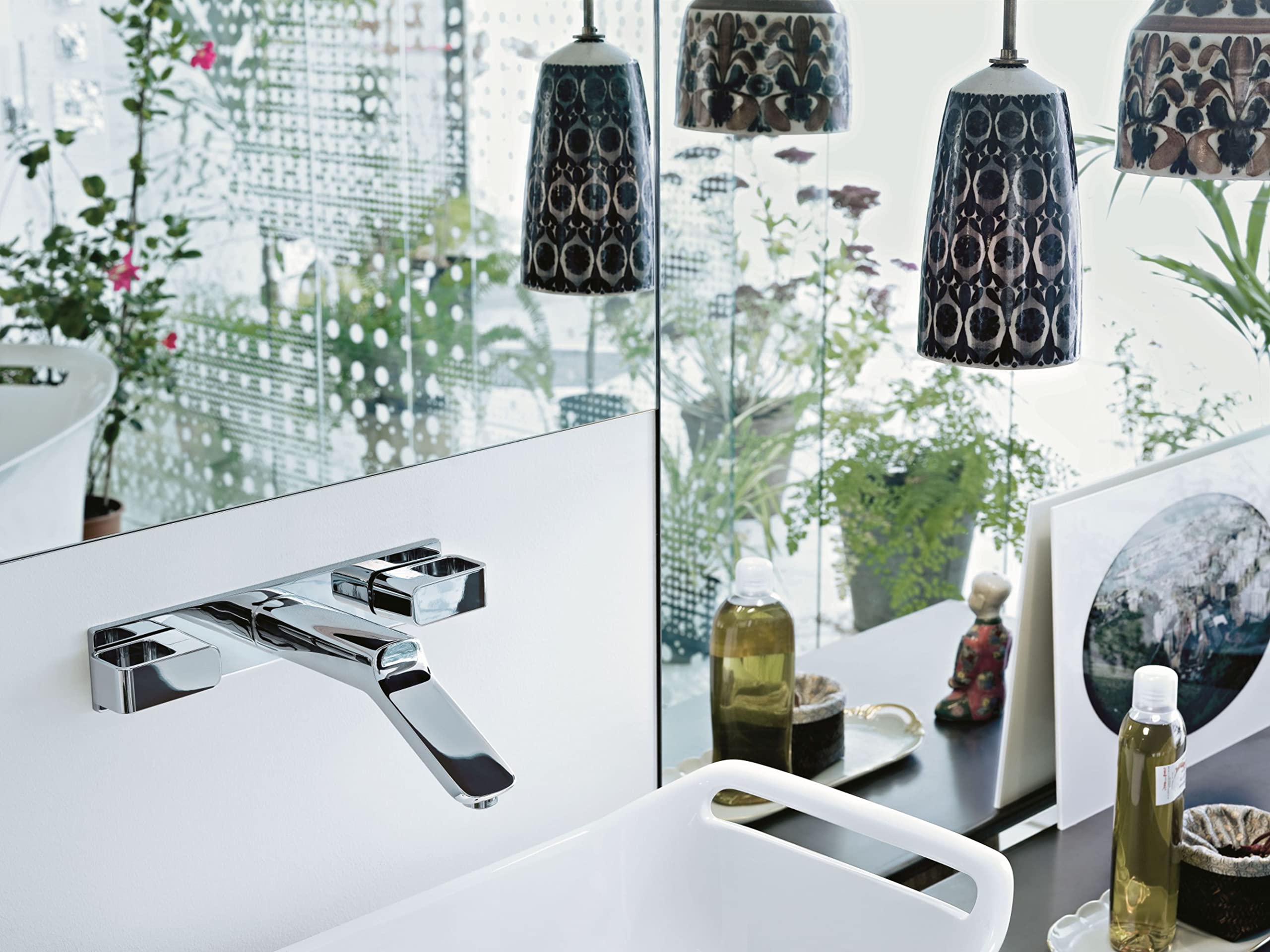 Chrome wall-mounted faucet trim with widespread spout and base plate installed on white bathroom sink.