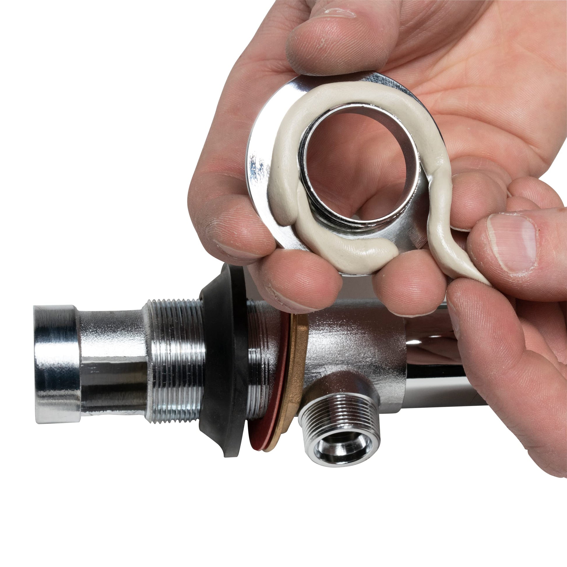 Tan plumber's putty being applied to a metal pipe fitting by hand.