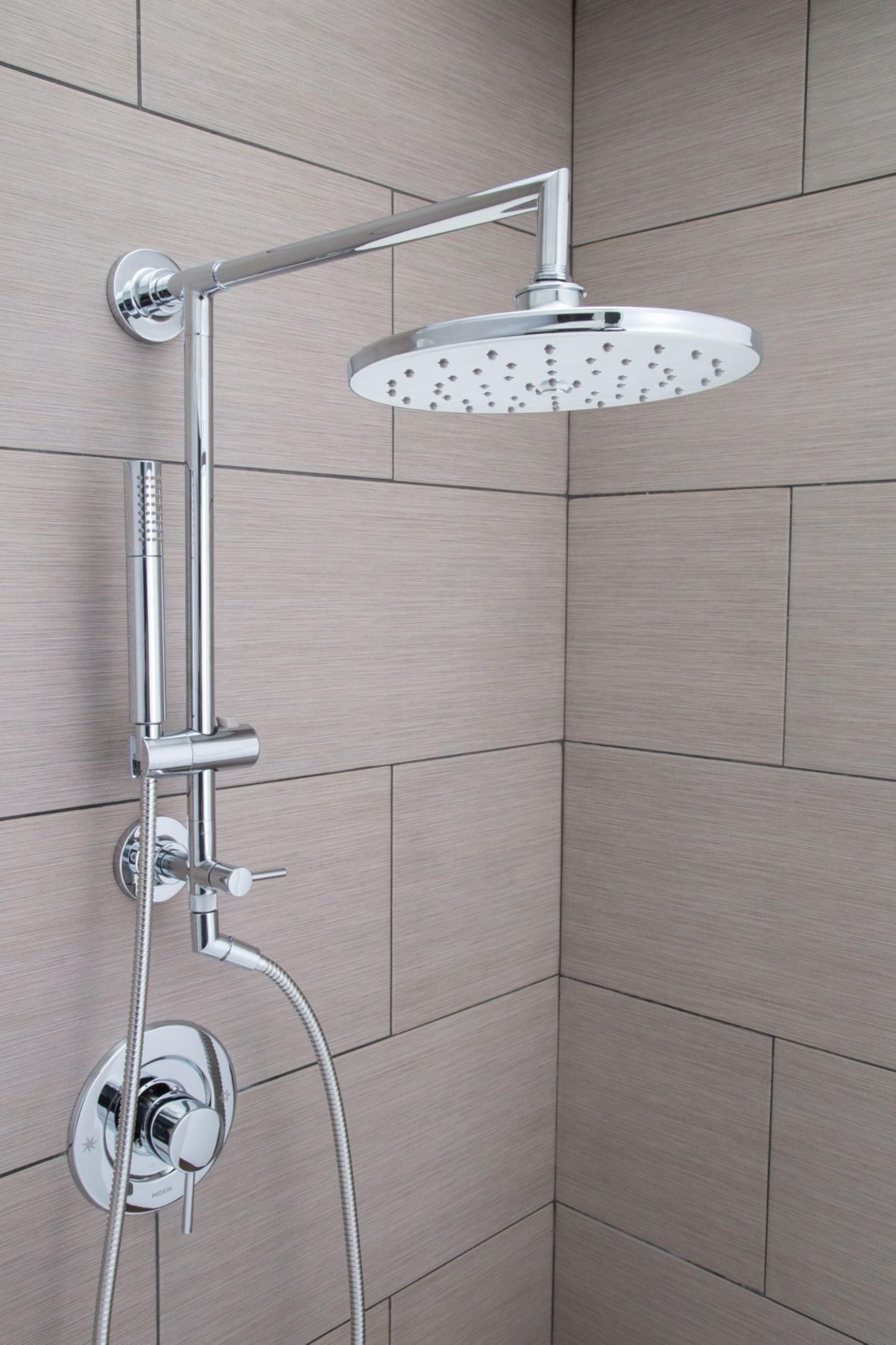 Chrome shower system with overhead rainfall showerhead, slidebar, handheld showerhead, and valve controls mounted on tile wal