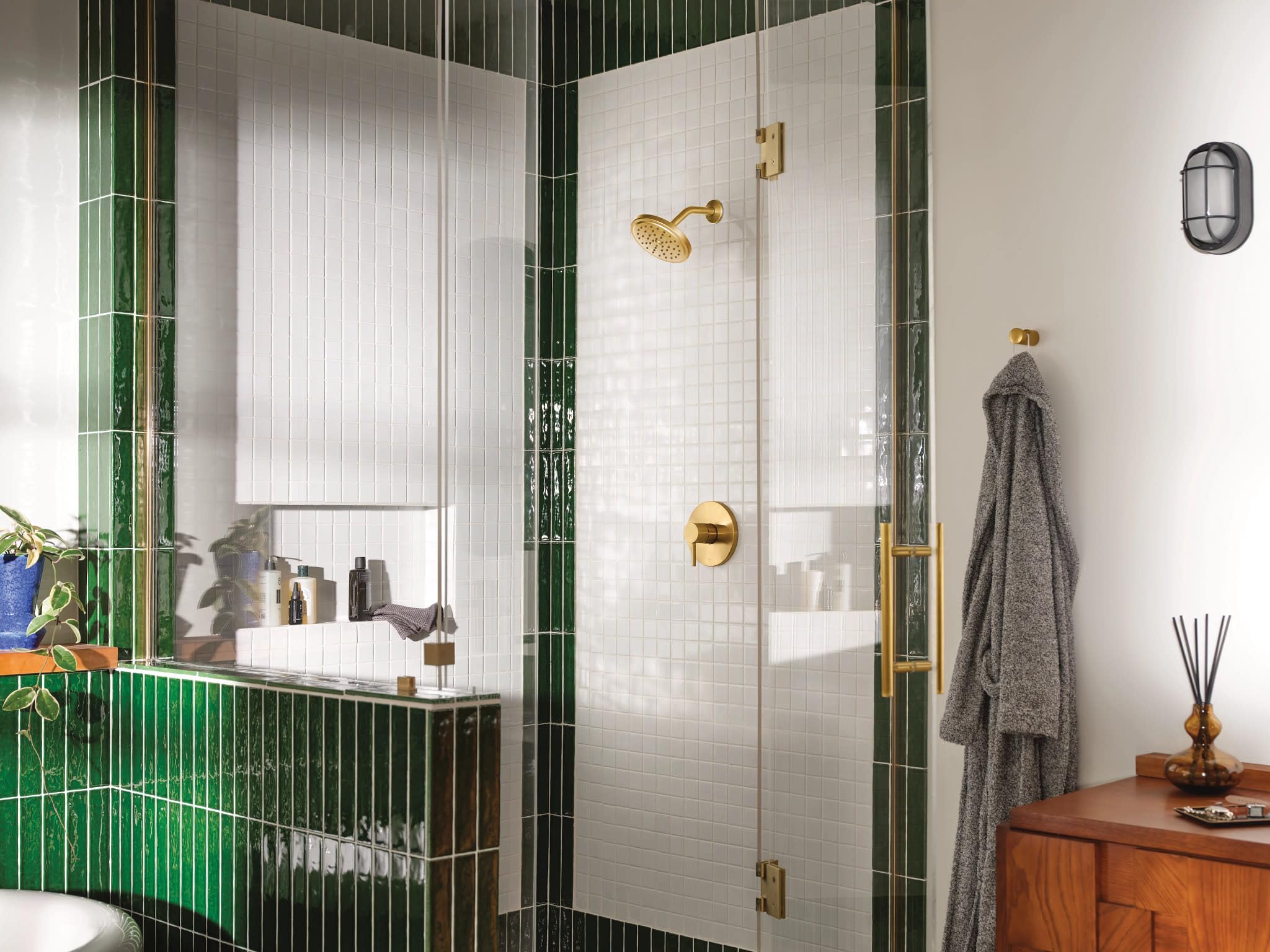 Brushed gold shower trim with wide showerhead and lever handle installed on white subway tile shower enclosure wall.