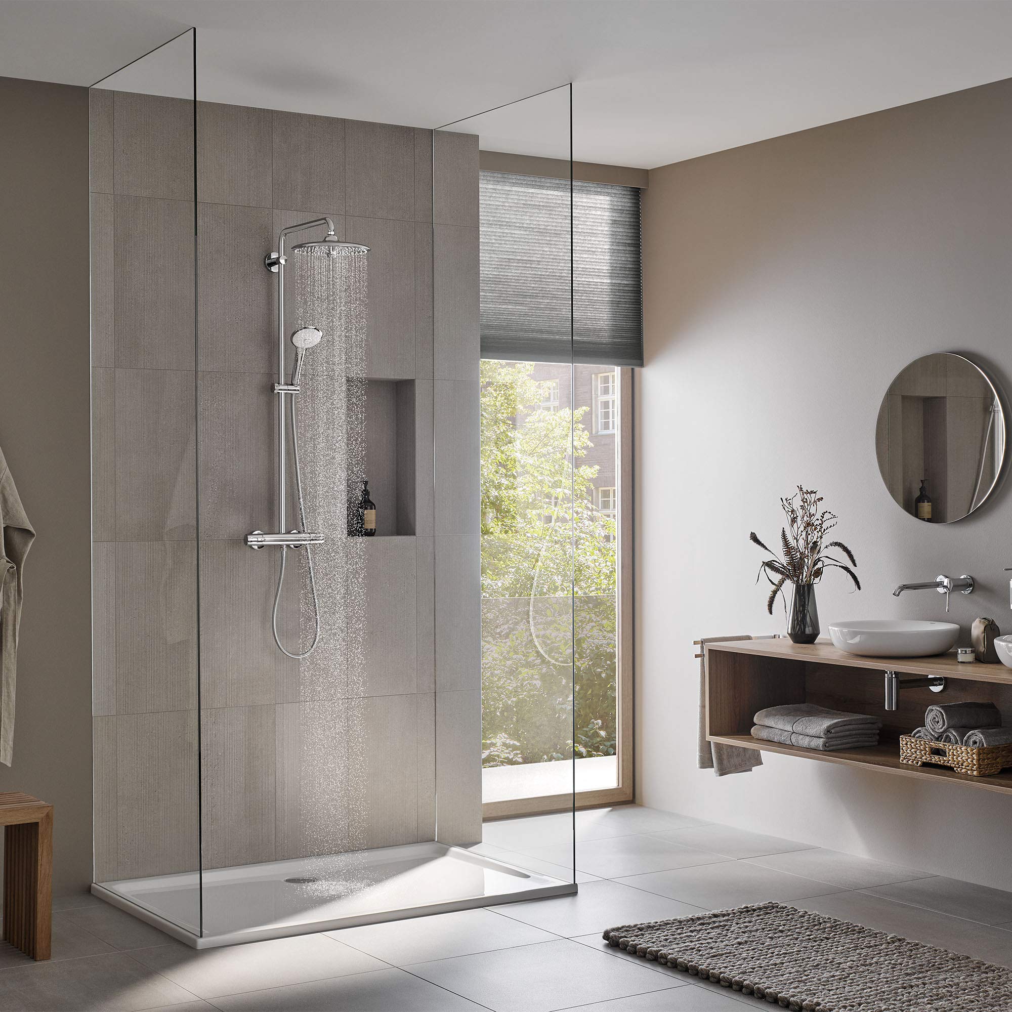 Chrome thermostatic shower system with overhead and handheld showerheads mounted on gray tile shower wall with glass enclosur
