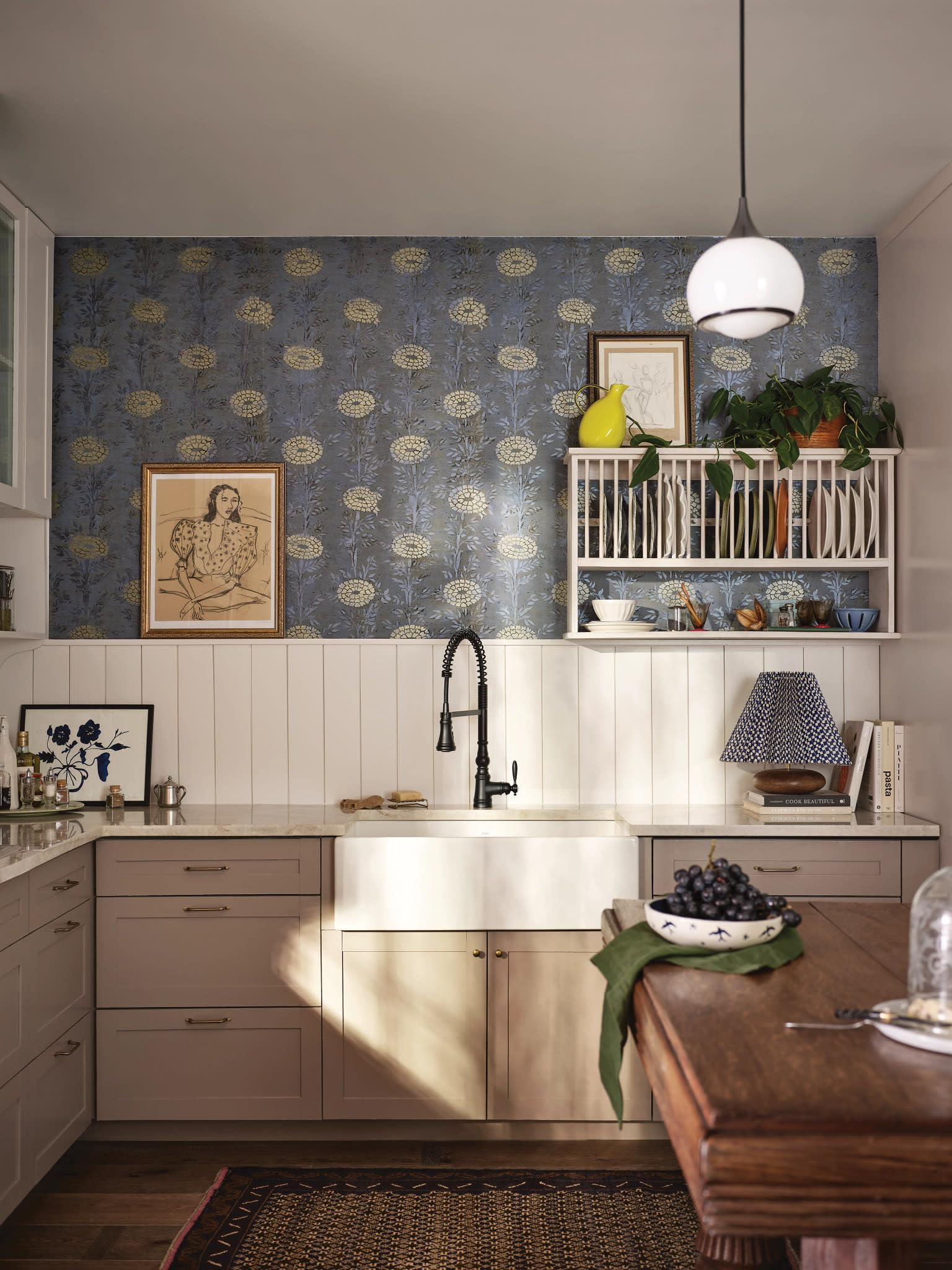 Matte black kitchen faucet with pulldown sprayer and curved handle mounted above white farmhouse sink.
