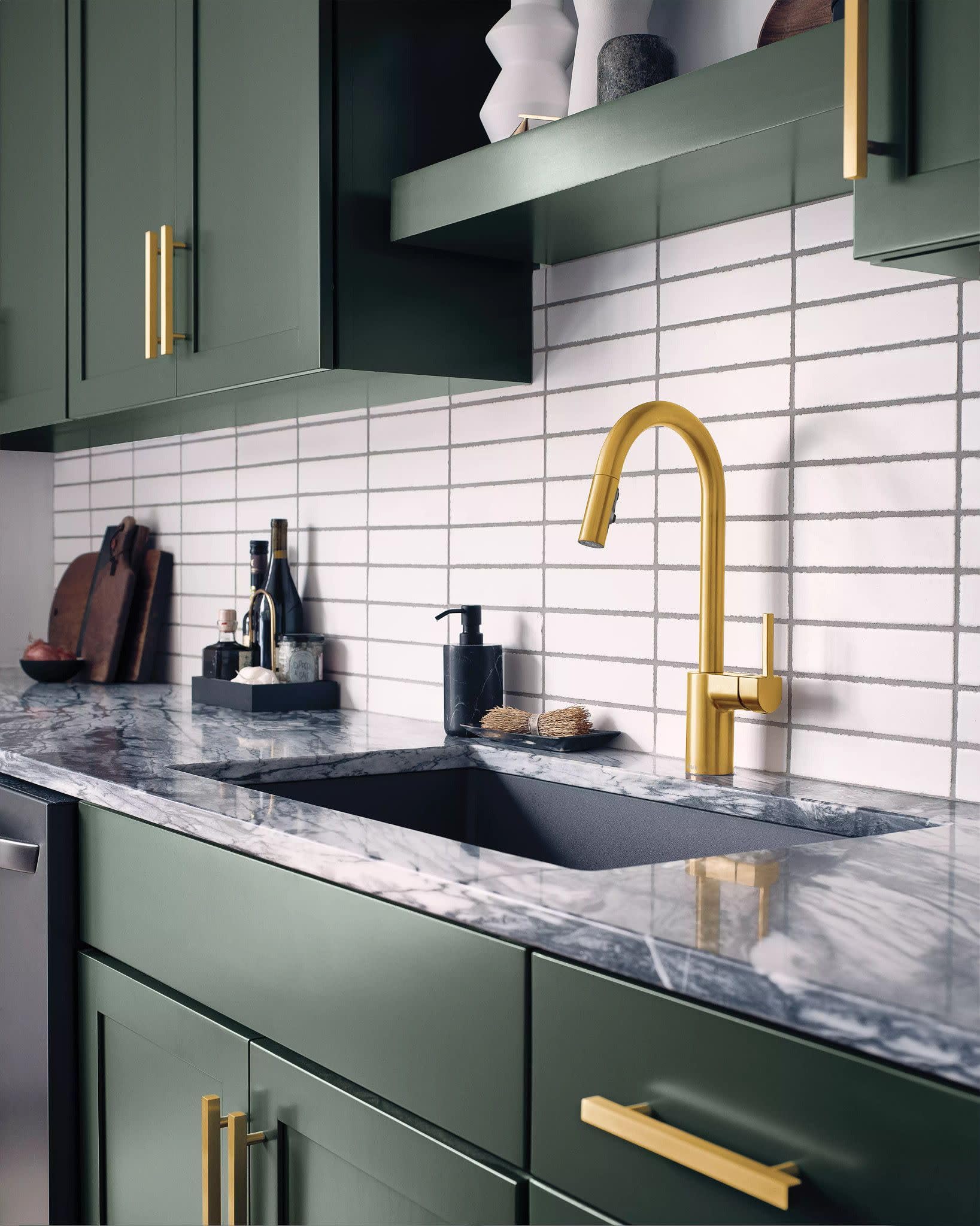 Brushed gold single-handle pulldown kitchen faucet with curved spout over a black sink in a marble countertop.
