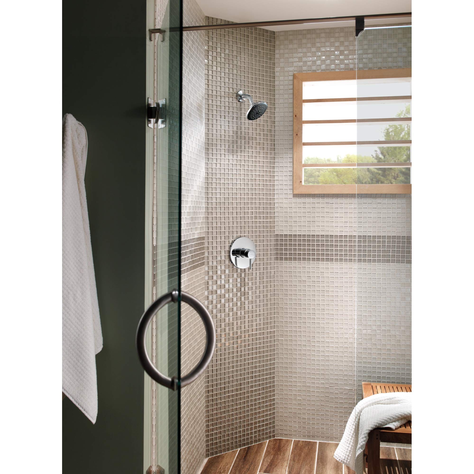 Chrome robe hook mounted on dark green wall beside shower enclosure with white towel hanging.
