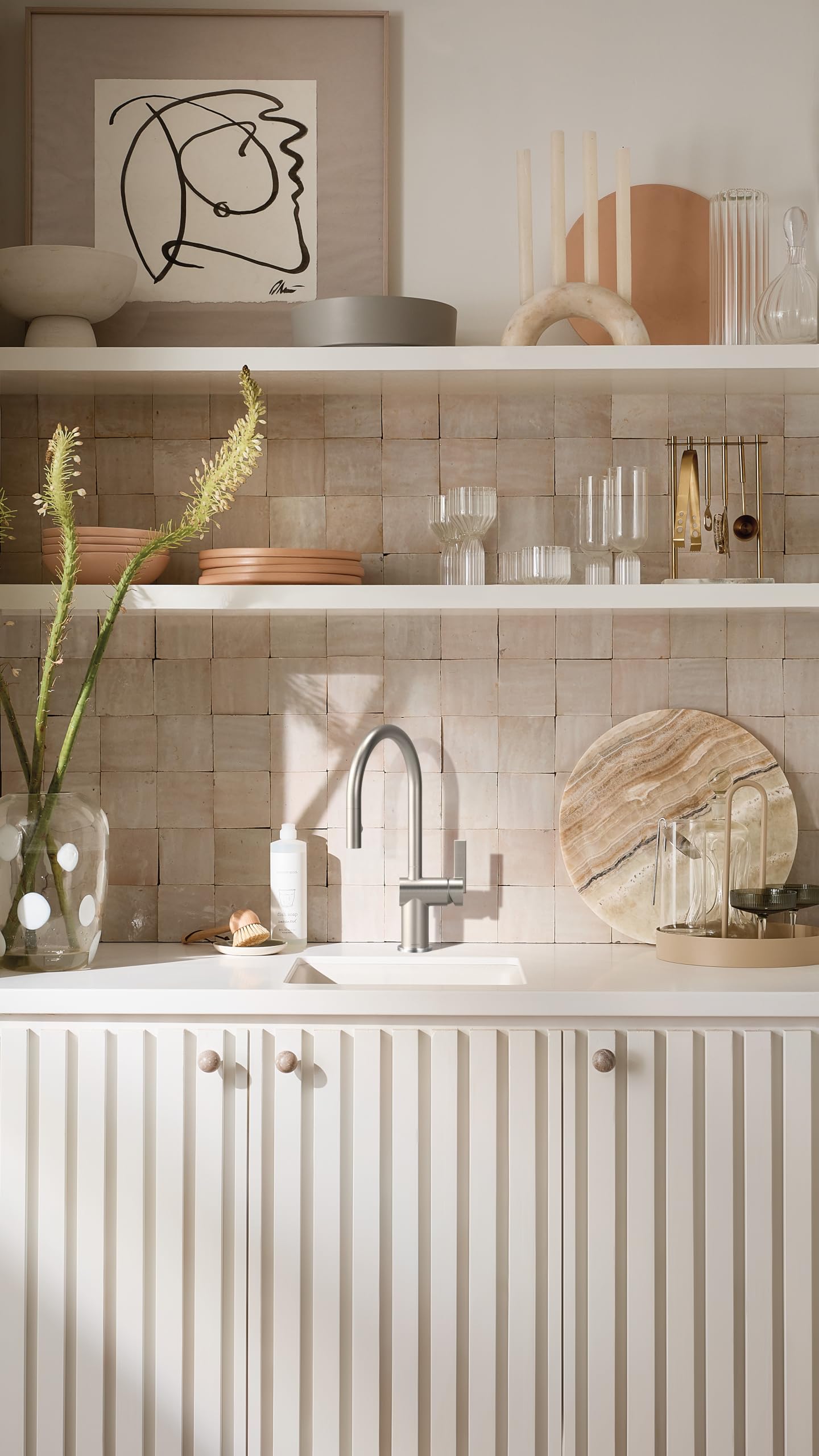 Stainless steel pulldown kitchen faucet with curved spout installed above white sink on tiled backsplash.