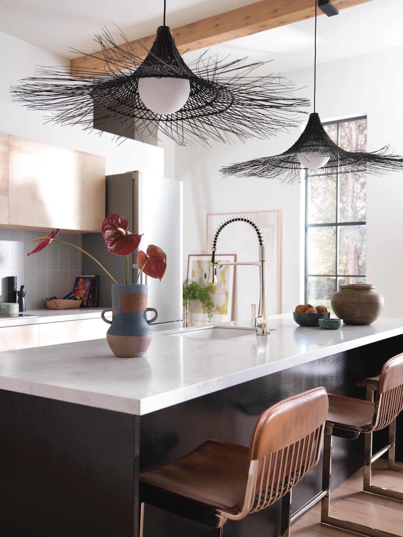 Polished nickel single-handle kitchen faucet with high arc spout and pulldown sprayer head installed at kitchen sink.