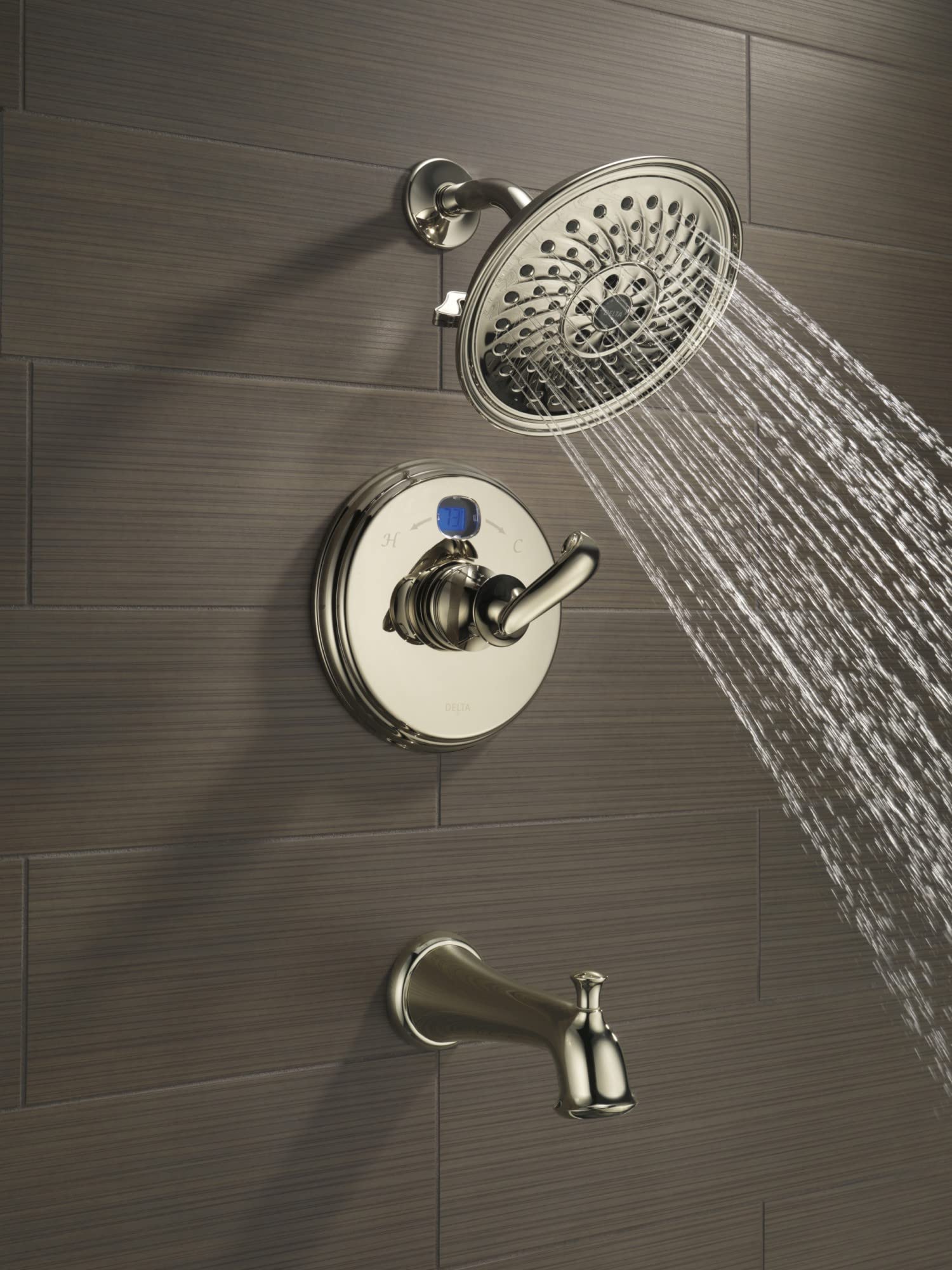 Chrome tub spout with pull-up diverter mounted on tile wall below showerhead and valve trim.