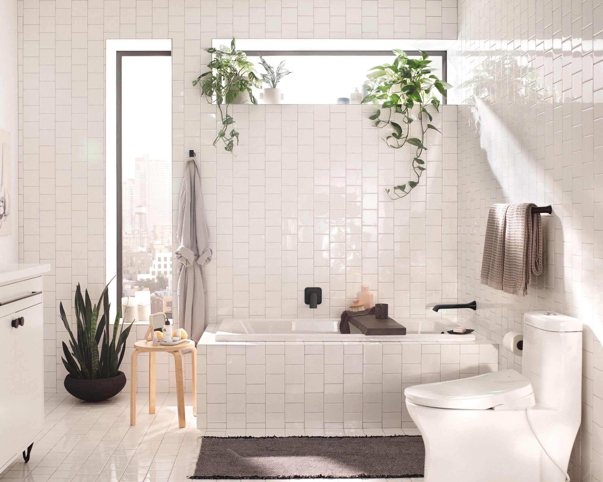 Black wall-mount towel bar installed horizontally above bathtub in white tile bathroom.